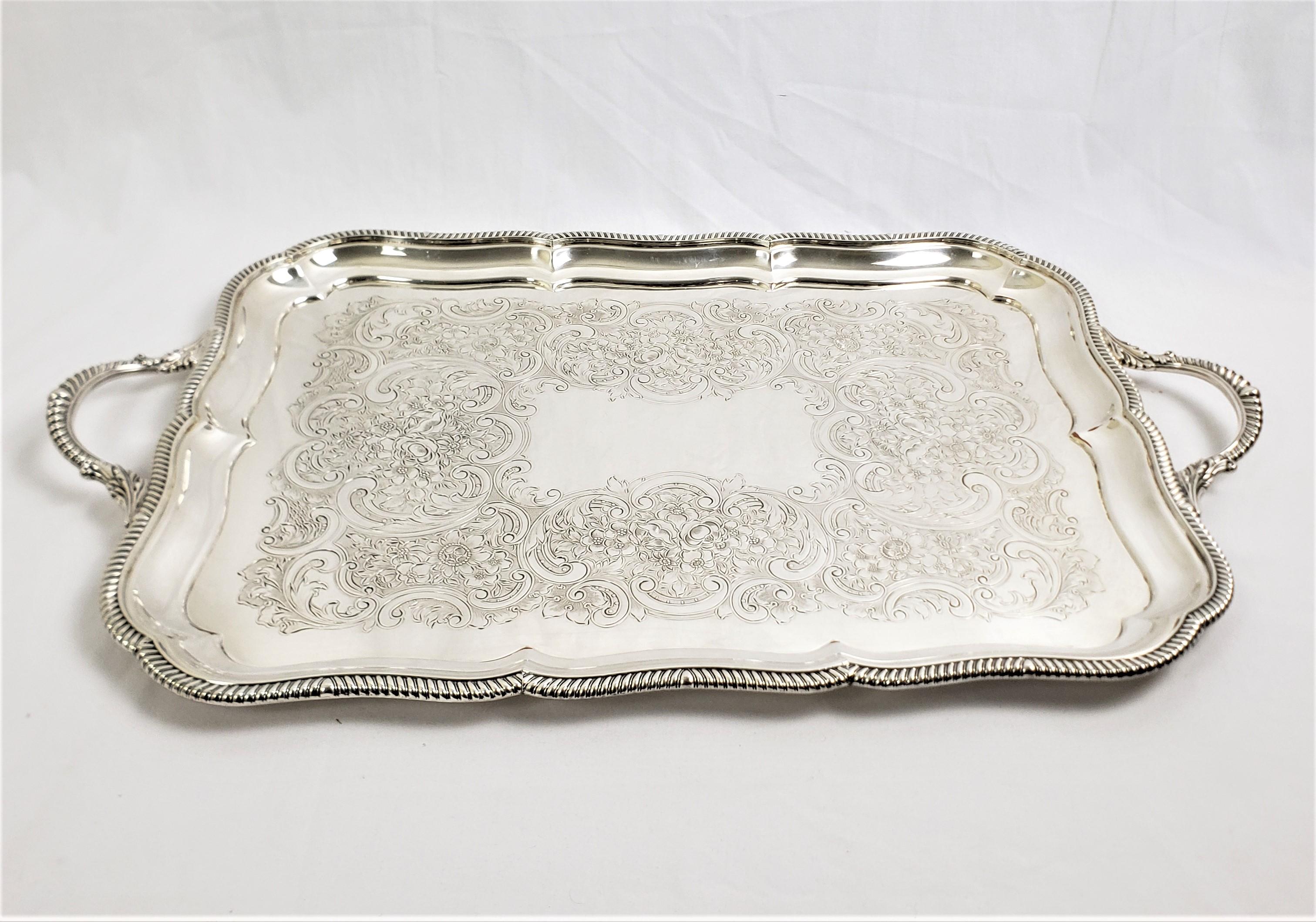 This antique rectangular silver plated serving tray was made by the well known Barker Ellis Silver Co. of England in approximately 1920 in a period Art Deco style. The tray is done with a stylized rope surround, which is accented on the handles with