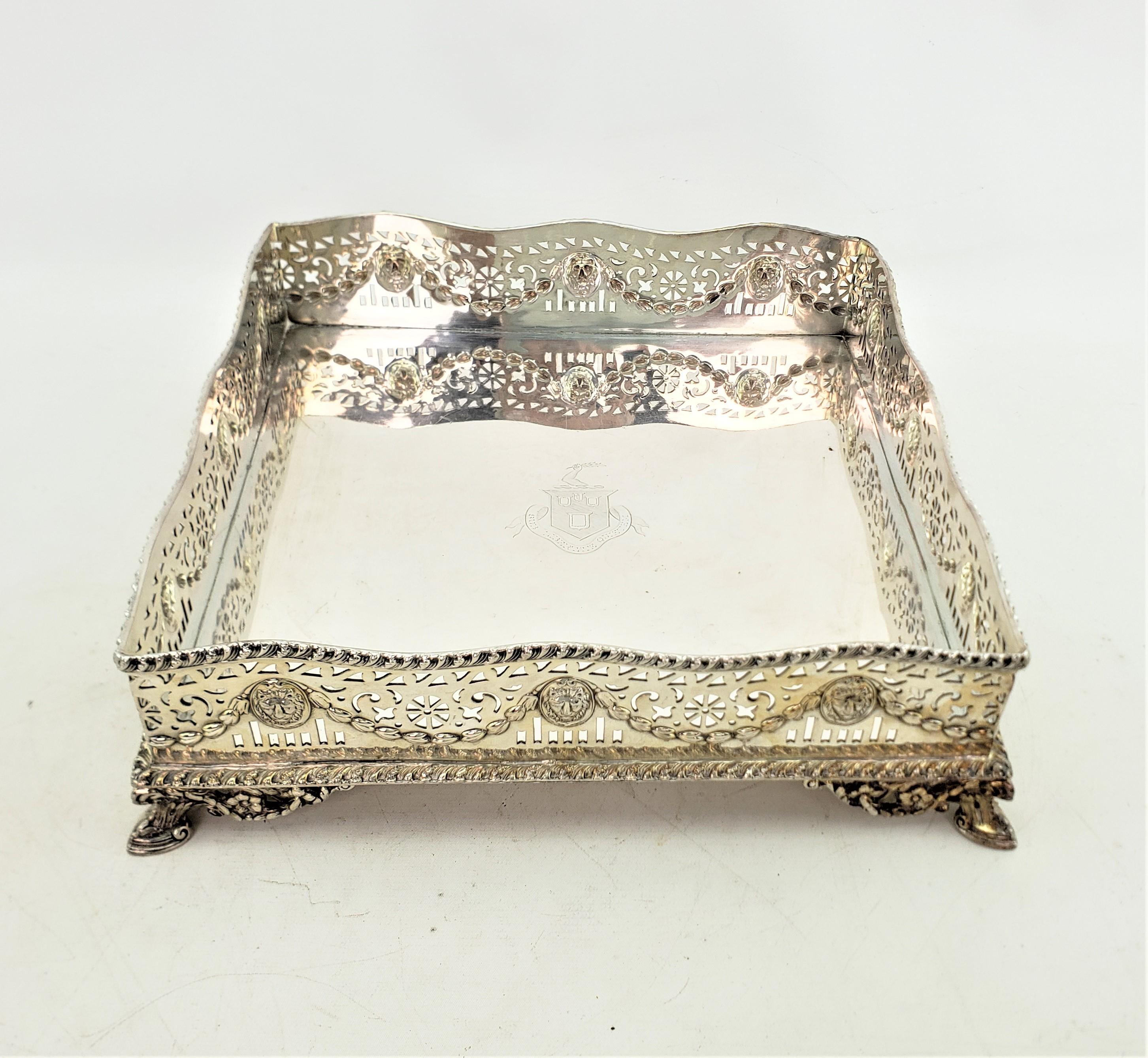 This antique gallery serving or bar tray was made by the renowned Barker-Ellis company of England in approximately 1920 in a Victorian style. The tray is composed of silver plate and done in a unique square shape with a high pierced gallery with a