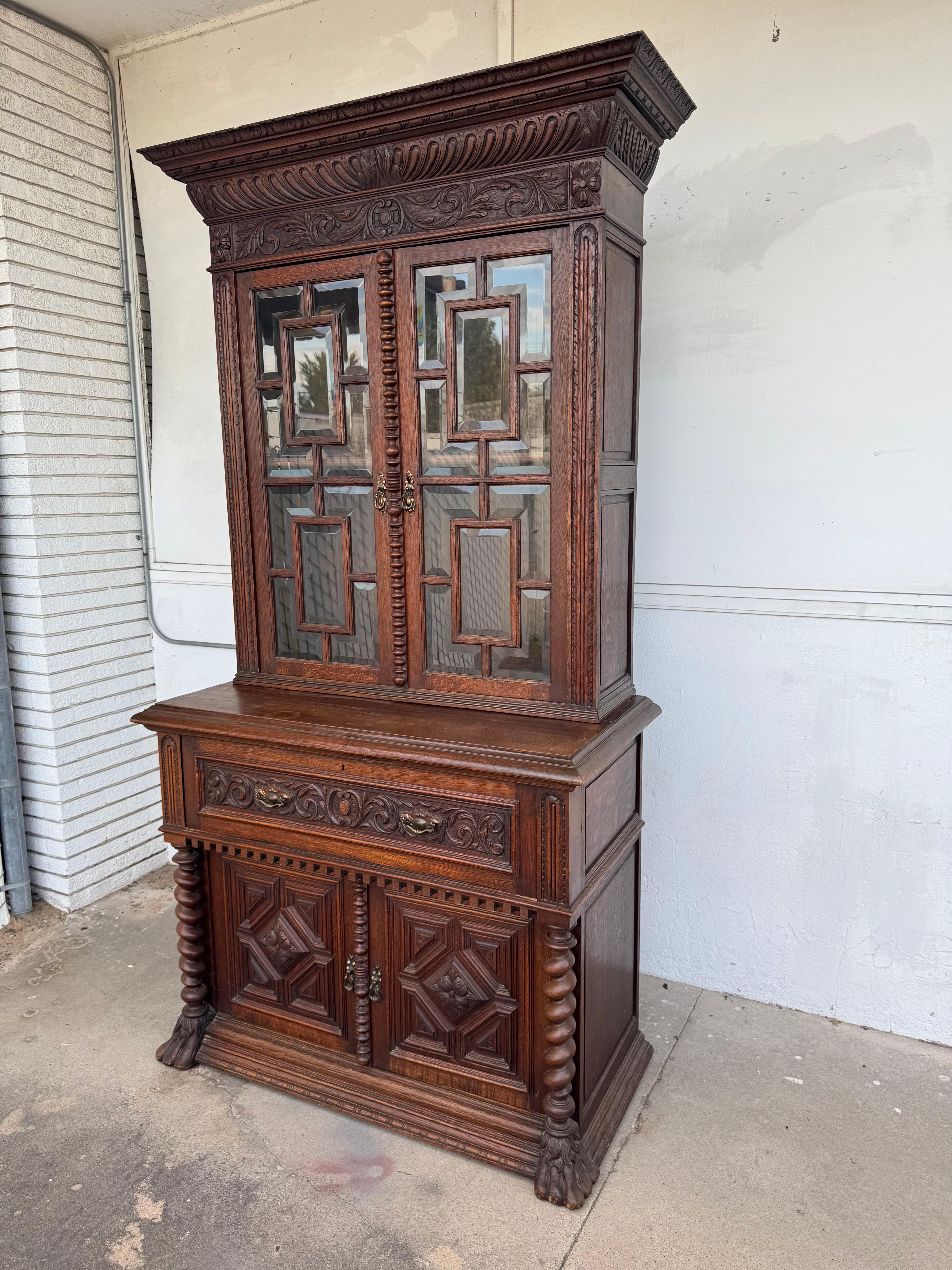 This cabinet/secretary comes from England.
The cabinet is made from English oak.
It is highly carved and boast barley twist columns.
The cabinet doors have beautiful fretwork wedged into the beveled glass.
The crest is highly carved as well as the