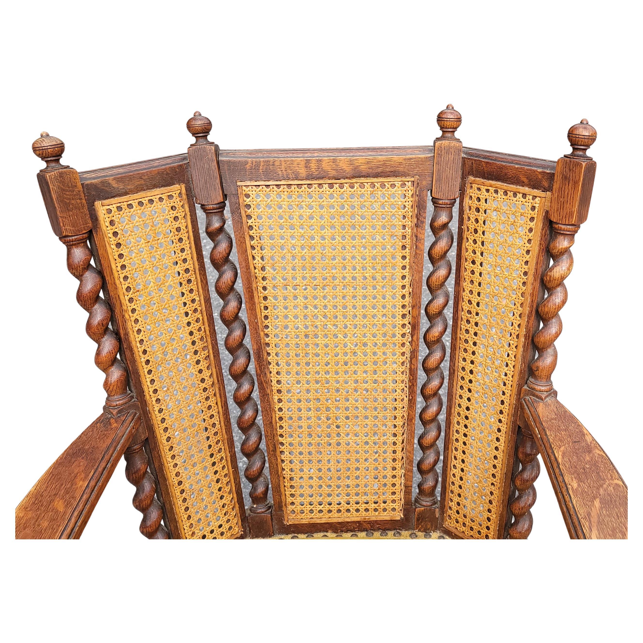 Antique chaise berçante Edouardienne à trois panneaux Caned Back with Barley Twist frame in mission oak. Le siège rembourré est ferme, mais il faut le rembourrer. Nous remeublerons le siège dans la couleur qui correspond le mieux à votre
