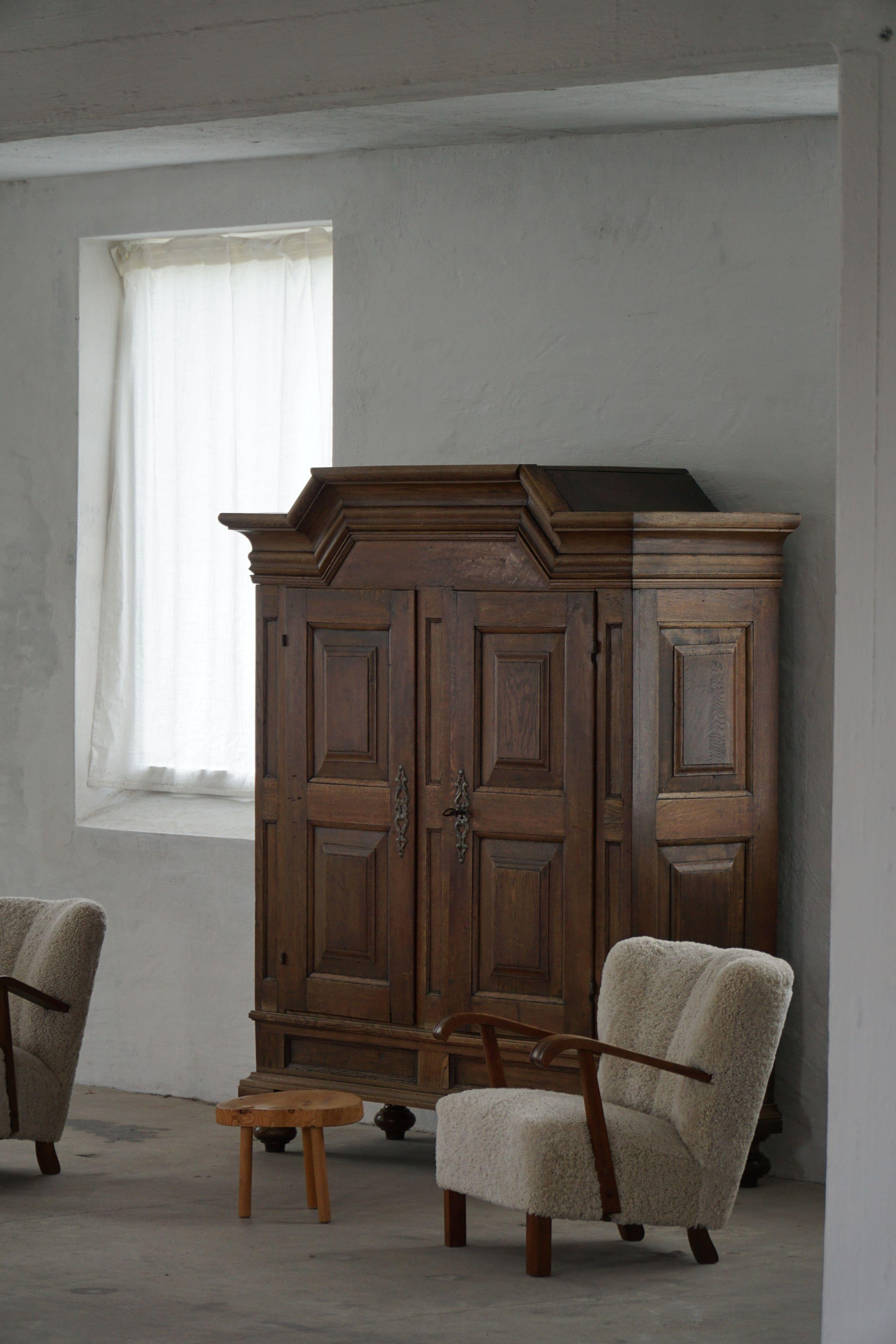 Exceptionnelle armoire danoise en chêne massif du XVIIIe siècle. L'extérieur présente des portes à panneaux classiques sous une corniche audacieuse, le chêne affichant une patine profonde et chaude acquise au cours de siècles d'utilisation. À