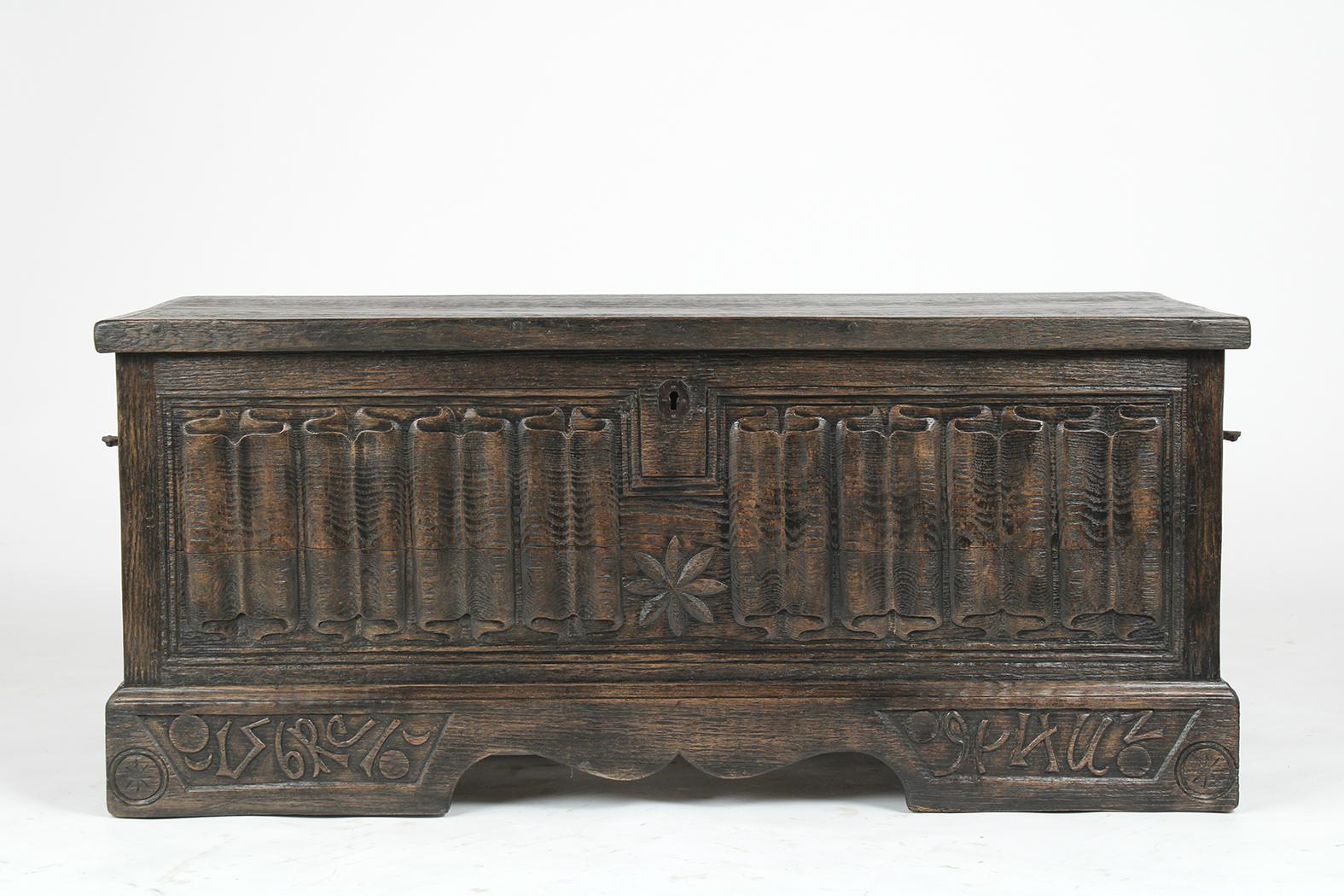 This Antique Baroque-style blanket trunk is in good condition made out of solid oak wood stained a dark walnut color with a patina finish and newly restored by our team of expert craftsmen. The trunk features a carved folding design along all sides,