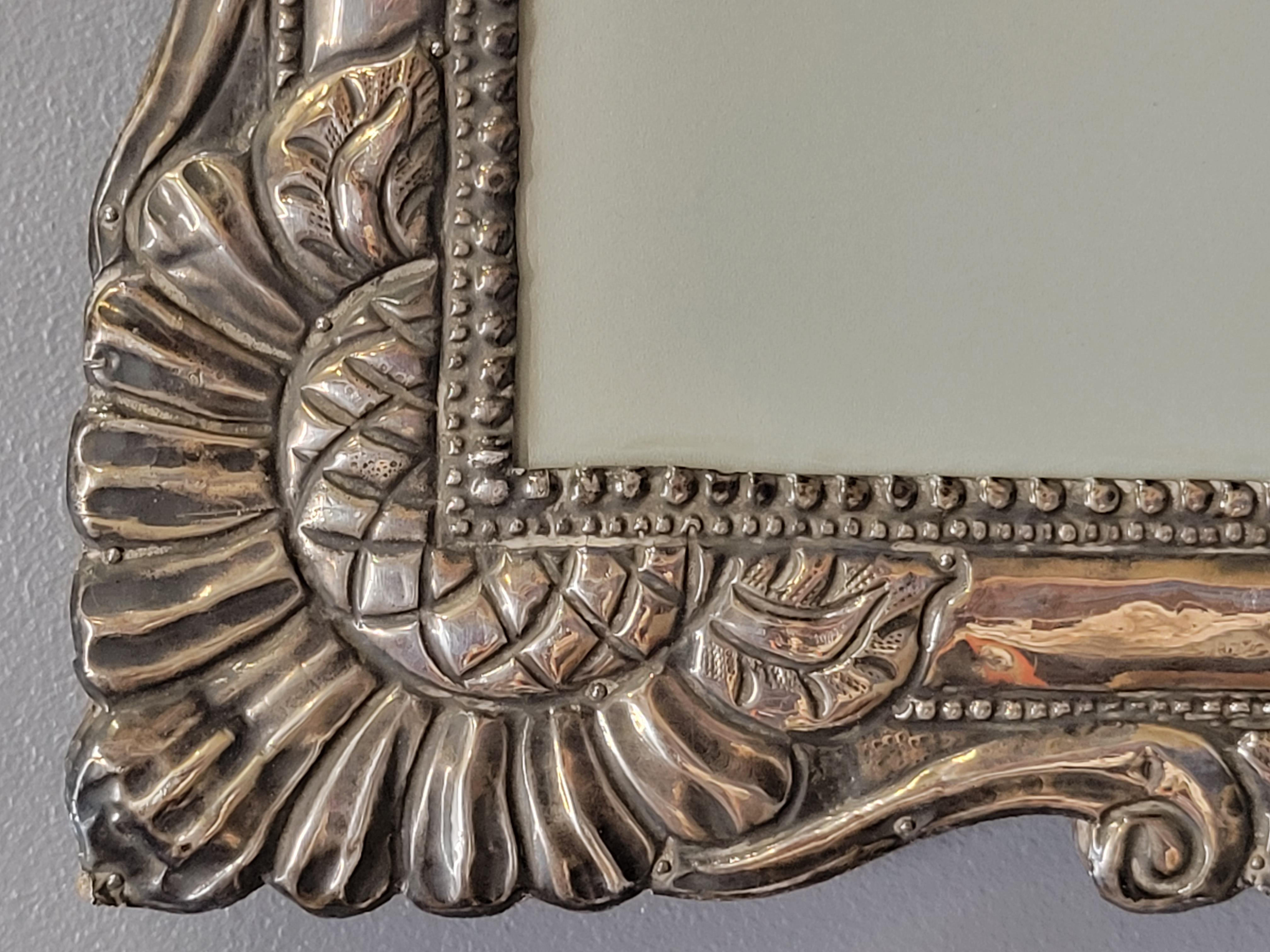 An absolutely stunning antique baroque hand hammered sterling silver picture frame that can be hung either vertically or horizontally. Likely from Mexico or South America, early 1900s or perhaps older. The silver was hand crafted and then attached