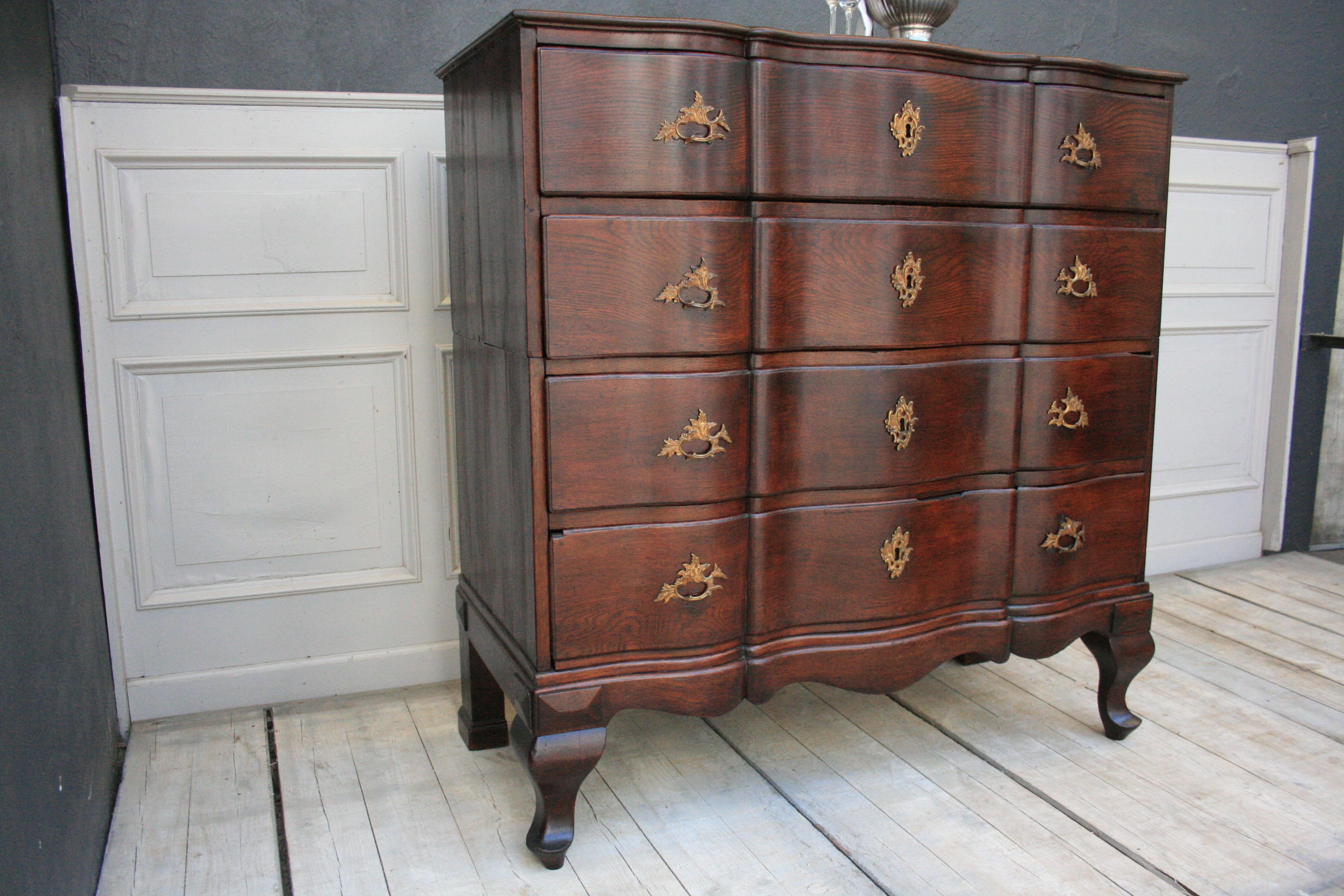 Original old baroque high chest of solid oak, northern Germany, circa 1750. Old restored. Two-divided (upper and lower part).
S-shaped sideways legs; cut out pedestal with small apron; moving front with double folding; original handles and key