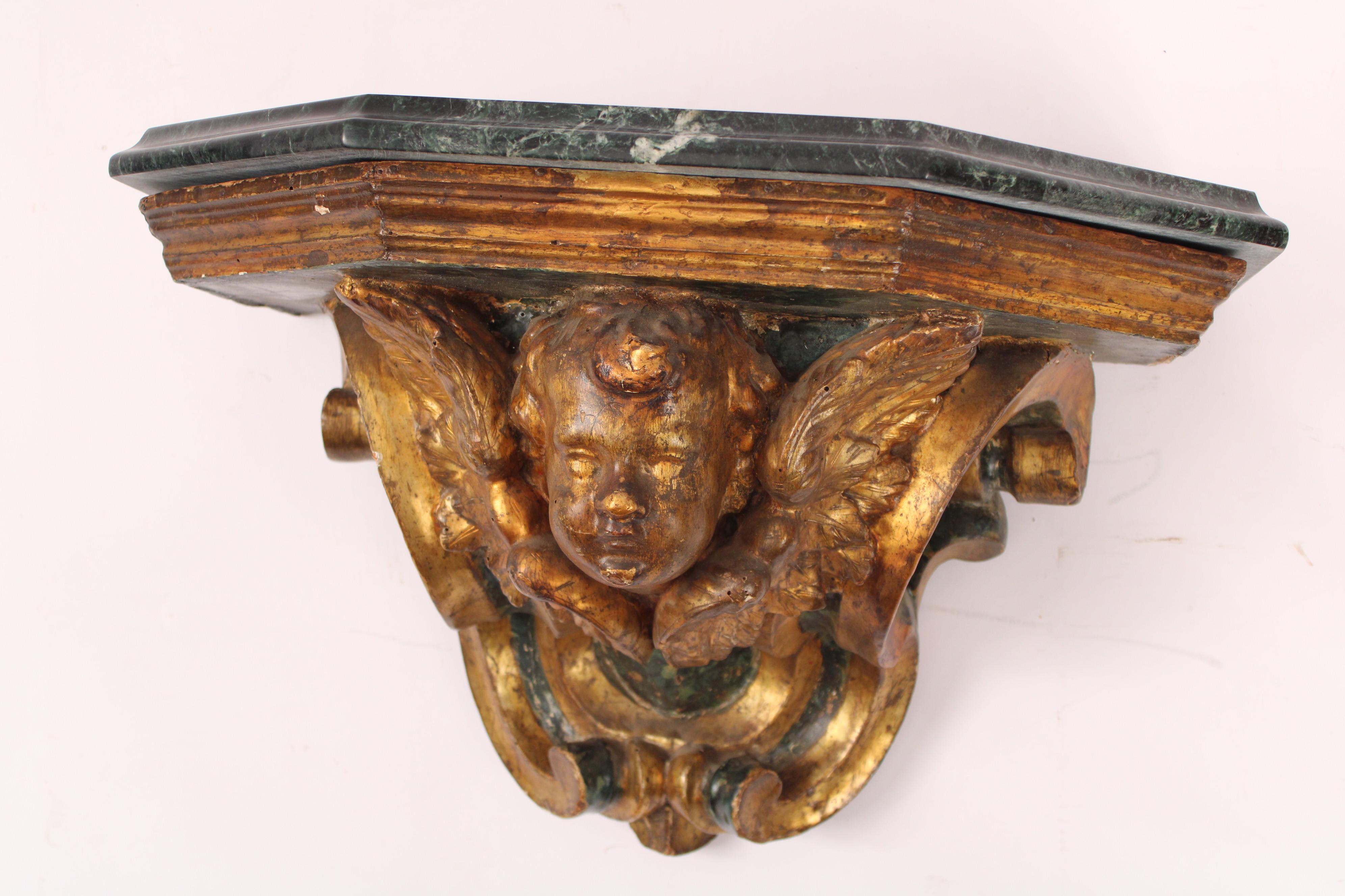 Antique baroque style painted and gilt decorated wall bracket, 18th century. With a mid to late 20th century marble top, a gilt decorated cupid face with wings.