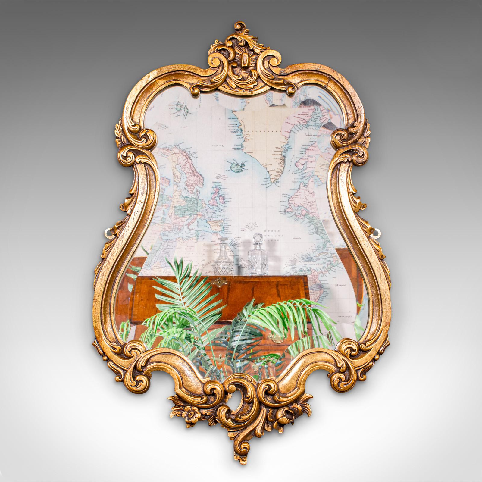 
This is an antique Baroque wall mirror. A French, ornate giltwood vanity mirror, dating to the Edwardian period, circa 1910.

Striking Baroque taste, ideal for the hall or boudoir
Displays a desirable aged patina and in good order
Carved giltwood