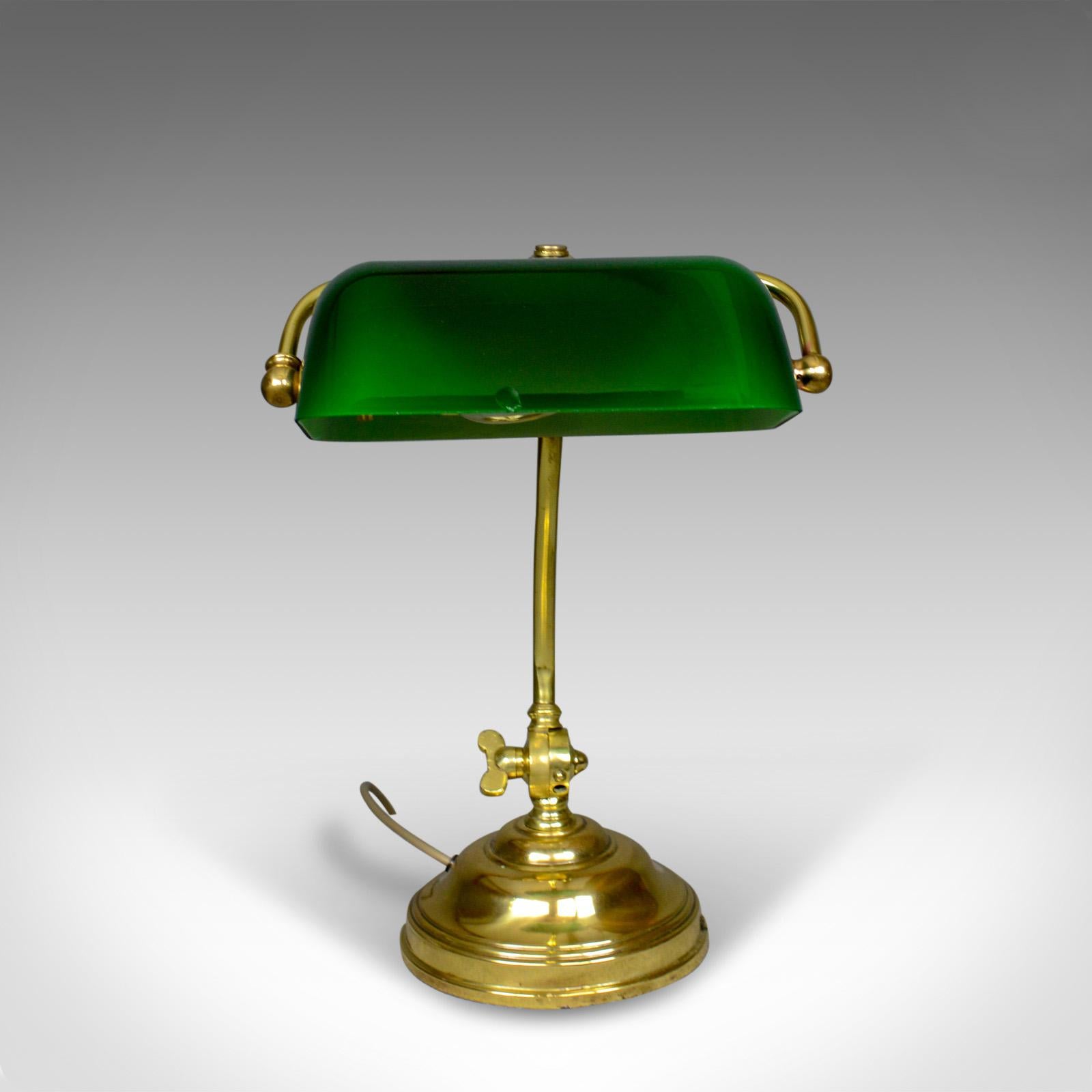 This is an antique barrister's desk lamp. A heavy, English, brass and glass lamp dating to the Edwardian period of the early 20th century, circa 1910.

Classic barristers desk lamp
Adjustable dark green glass shade
Minor chip to front edge of