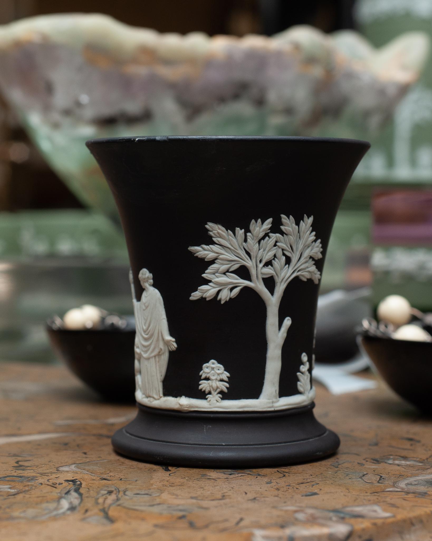 A stunning antique Wedgwood black Basalt Jasperware small vase with white overlay, circa 1964. Please note small chip in rim has been repaired previously and pictured in photos.