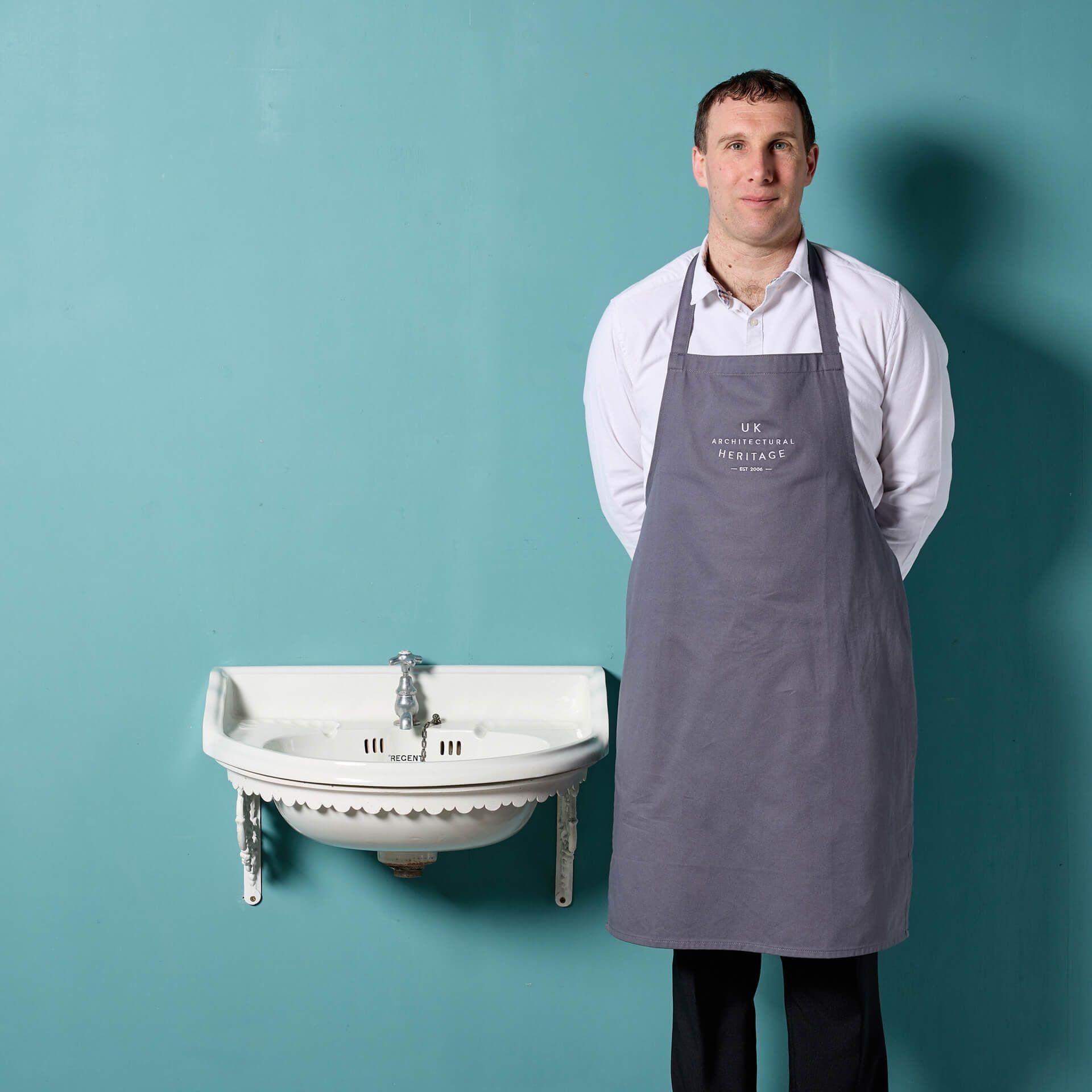 Un antico lavabo in porcellana con un rubinetto e una staffa a muro in ghisa. Questo lavello inglese è dotato di un rubinetto d'epoca in stile francese e decorato con un bordo smerlato, il che lo rende un reperto insolito. La staffa da parete in