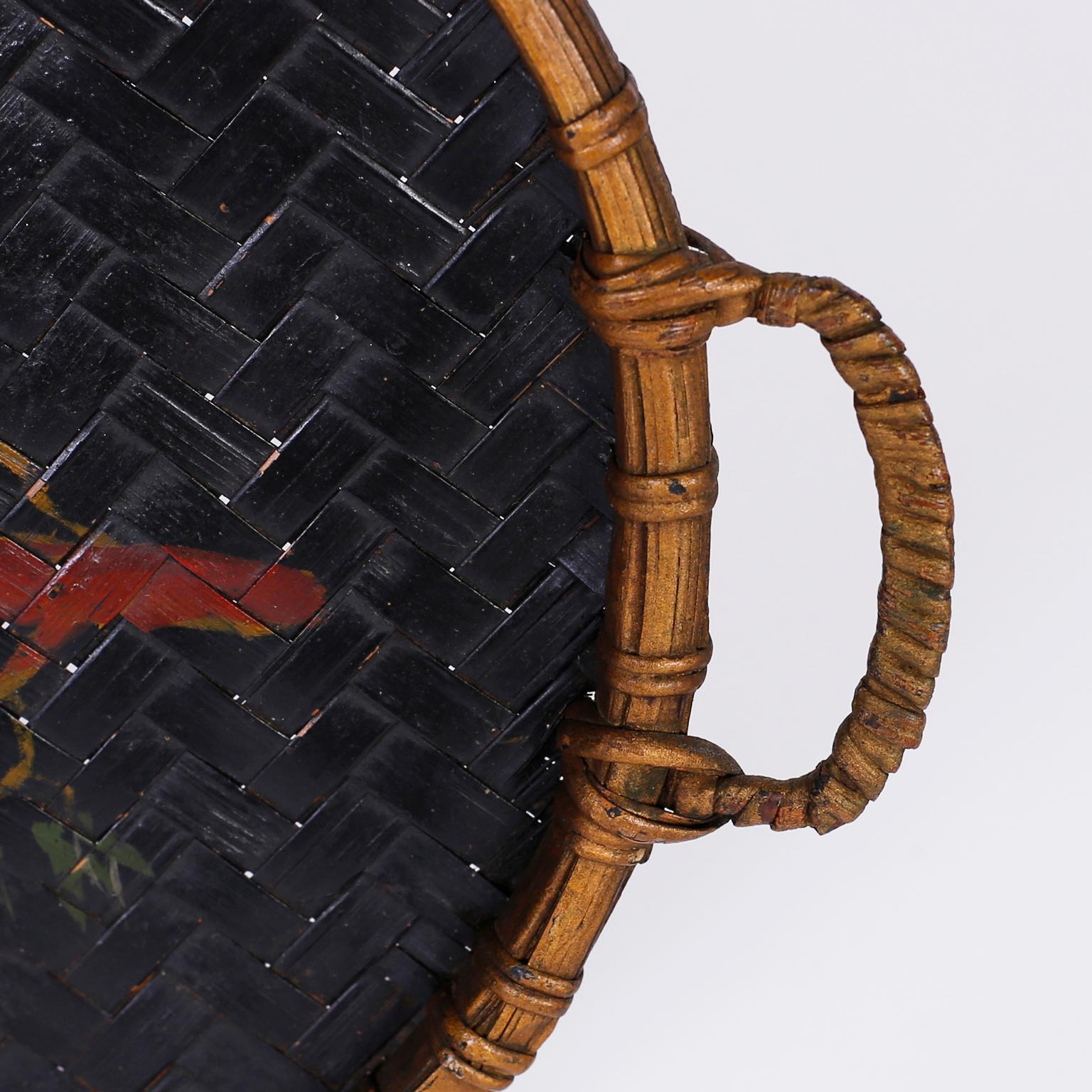 Plateau ou panier fait à la main avec une bordure en faux bambou, deux poignées et un perroquet folklorique peint sur un tissage à chevrons.