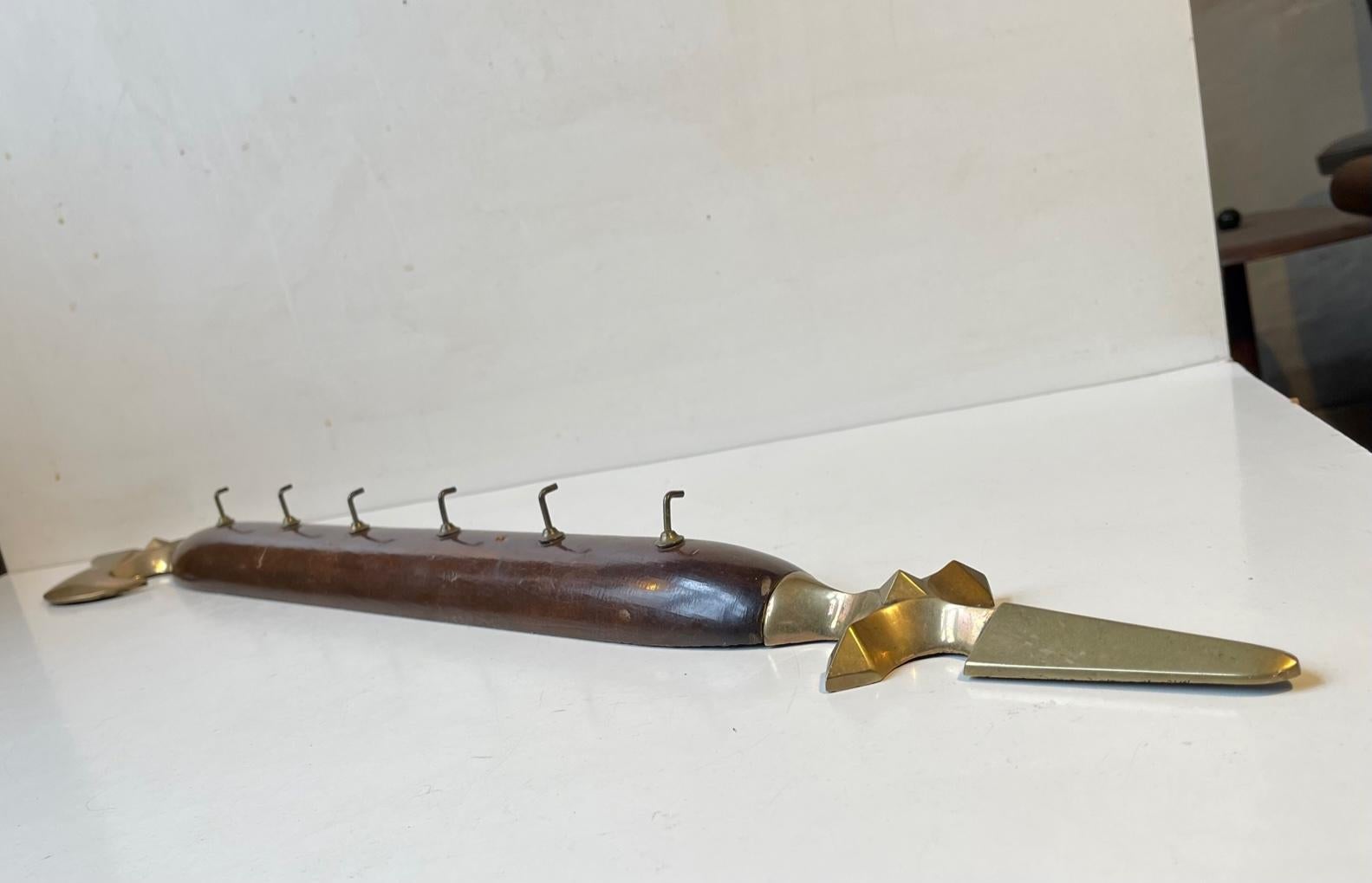 Decorative large key or dishtowel hanger in shape of an axe. It has 6 hooks and its made from brass and lacquered mahogany. A type not restricted by cites. It was made circa 1900-1920, probably to a Rotary or Mason's association. Measurements: L/W: