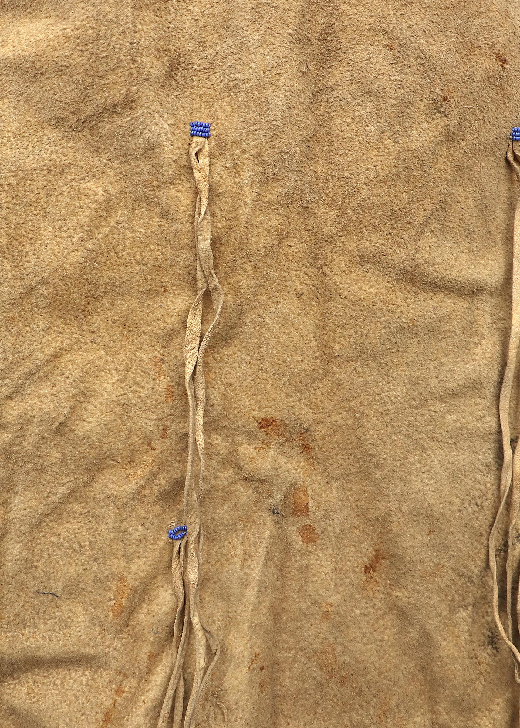 Robe d'enfant sioux avec jambières assorties. Créée à la main avec de la peau tannée indigène et perlée avec des perles de commerce en verre en bleu, blanc, rouge, rose et vert. Les éléments picturaux comprennent des motifs de croix et de Tipi