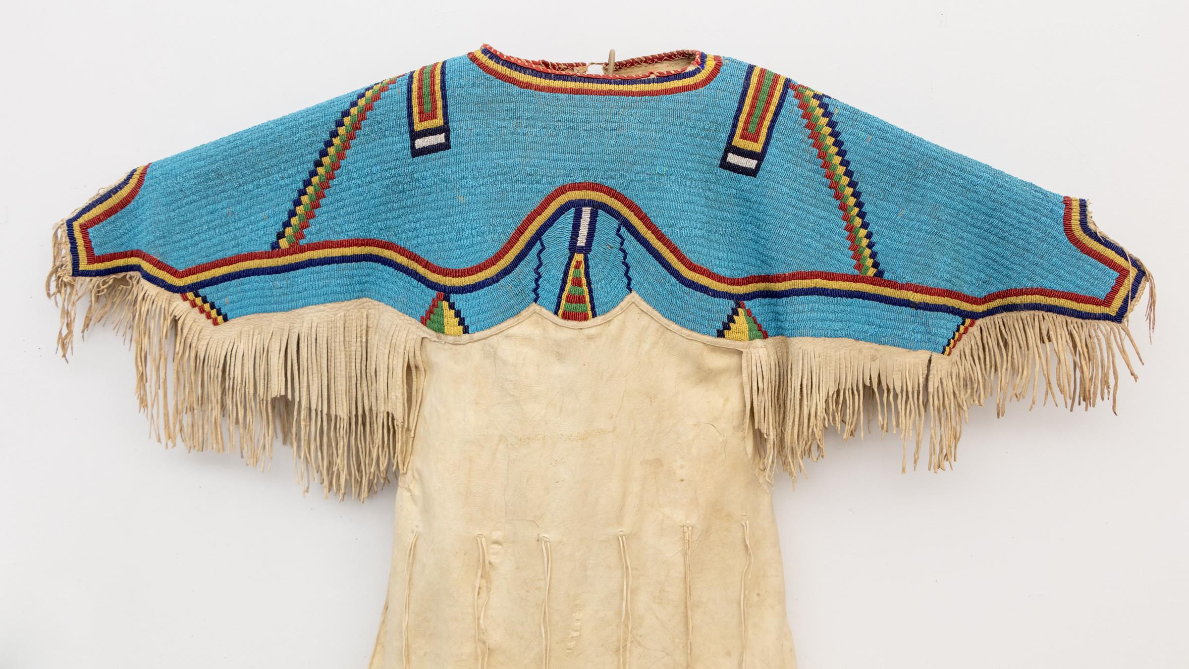 This extraordinary antique Sioux beaded hide dress, dating to circa 1880, is a rare and authentic example of Plains Indian textile art. Handcrafted from native-tanned deer hide, the dress is richly adorned with Venetian glass trade beads, showcasing