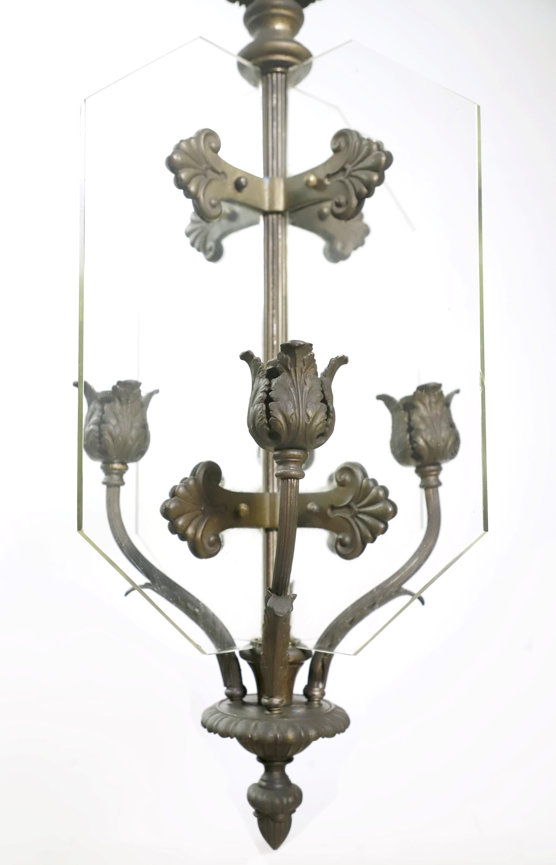 Early 20th century bronze pendant chandelier in a Classic Beaux Arts design. Each of the four standard medium bass sockets are separated by glass panels. Comes with original canopy. This light will be cleaned and rewired before shipping. Please