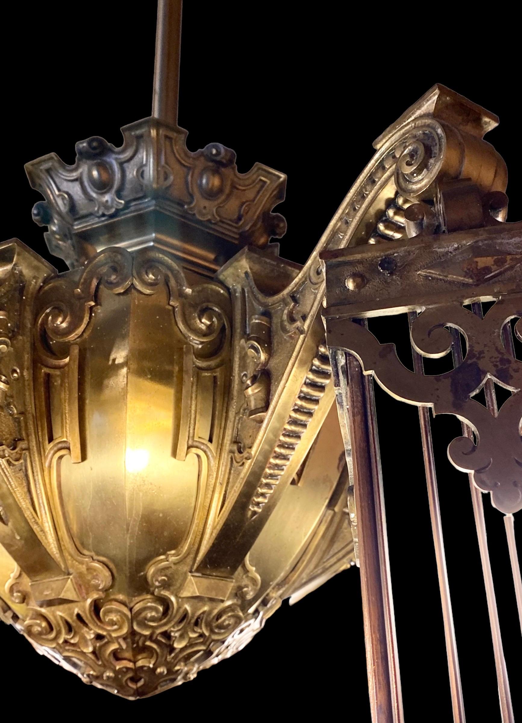 This rare and stately copper, bronze and brass period Beaux Arts chandelier features six stunning, heavy scrolling arms which are highly adorned with geometric and beaded designs. Six original and highly detailed copper and art glass lanterns hang