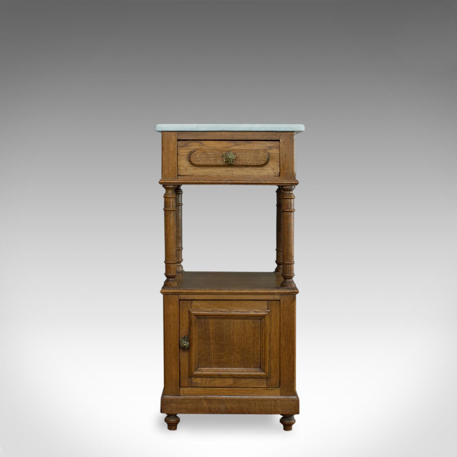 This is an antique bedside cabinet. A French, oak and marble, lamp nightstand table dating to the early 20th century, circa 1930.

Select oak with wisps of medullary rays and fine grain interest
Rich consistent whiskey hues and a desirable aged