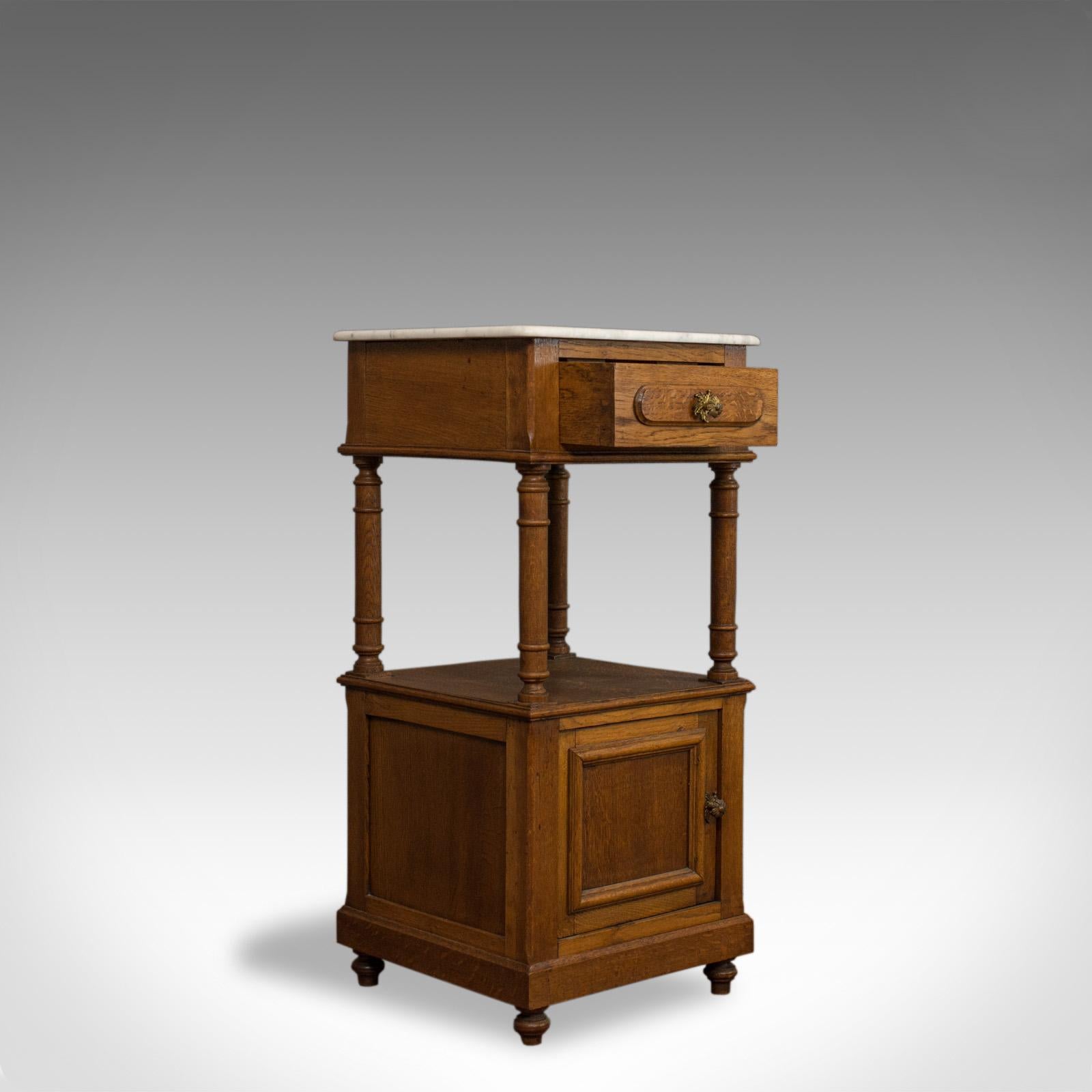 This is an antique bedside cabinet. A French, oak and marble lamp nightstand table dating to the early 20th century, circa 1930.

Select oak with wisps of medullary rays and fine grain interest
Good consistent whiskey hues and a desirable aged