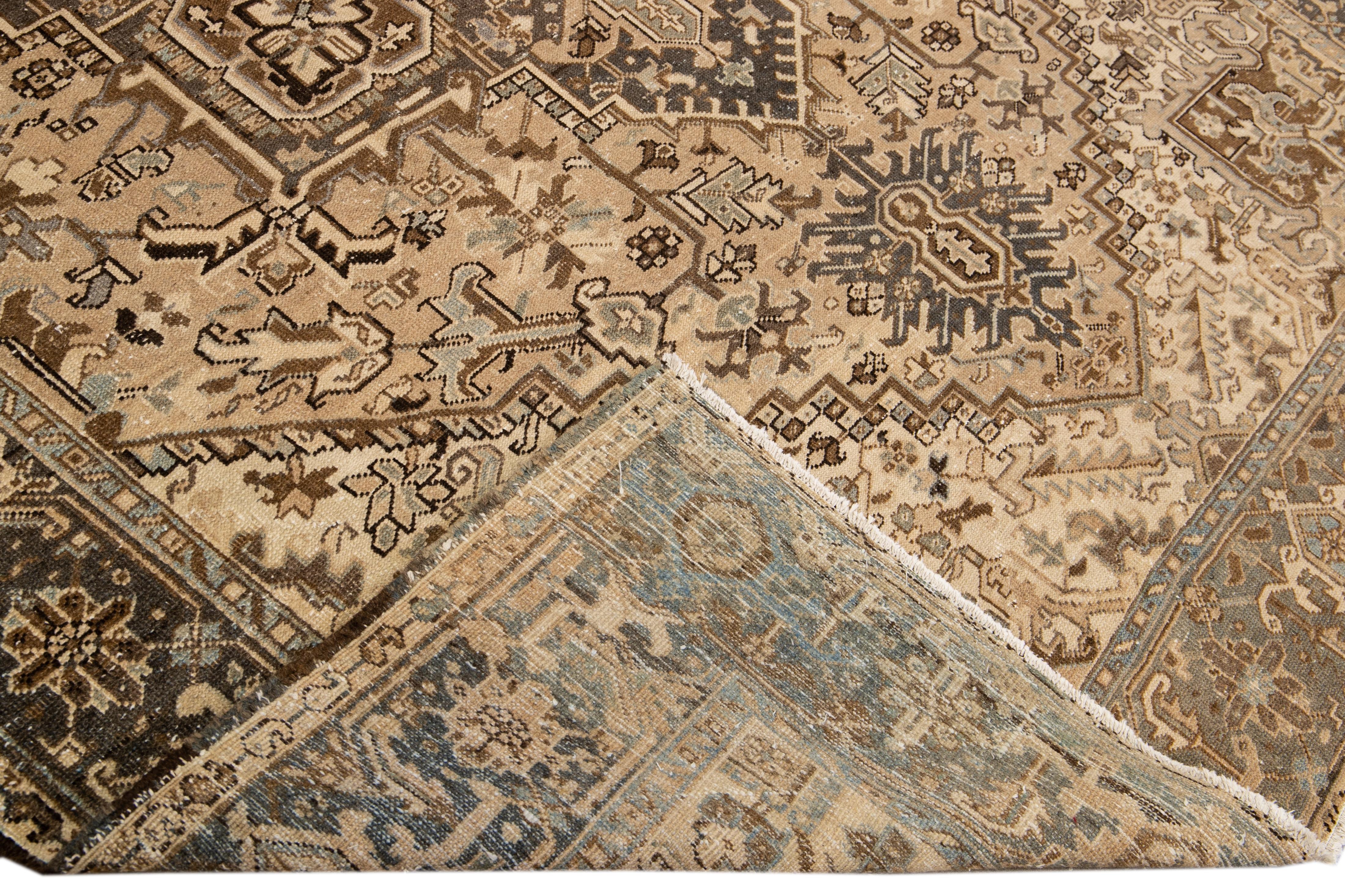 Beautiful antique Heriz hand-knotted wool rug with a beige field. This Persian rug has a blue frame and brown accents in a gorgeous all-over geometric floral motif.

This rug measures: 8'2