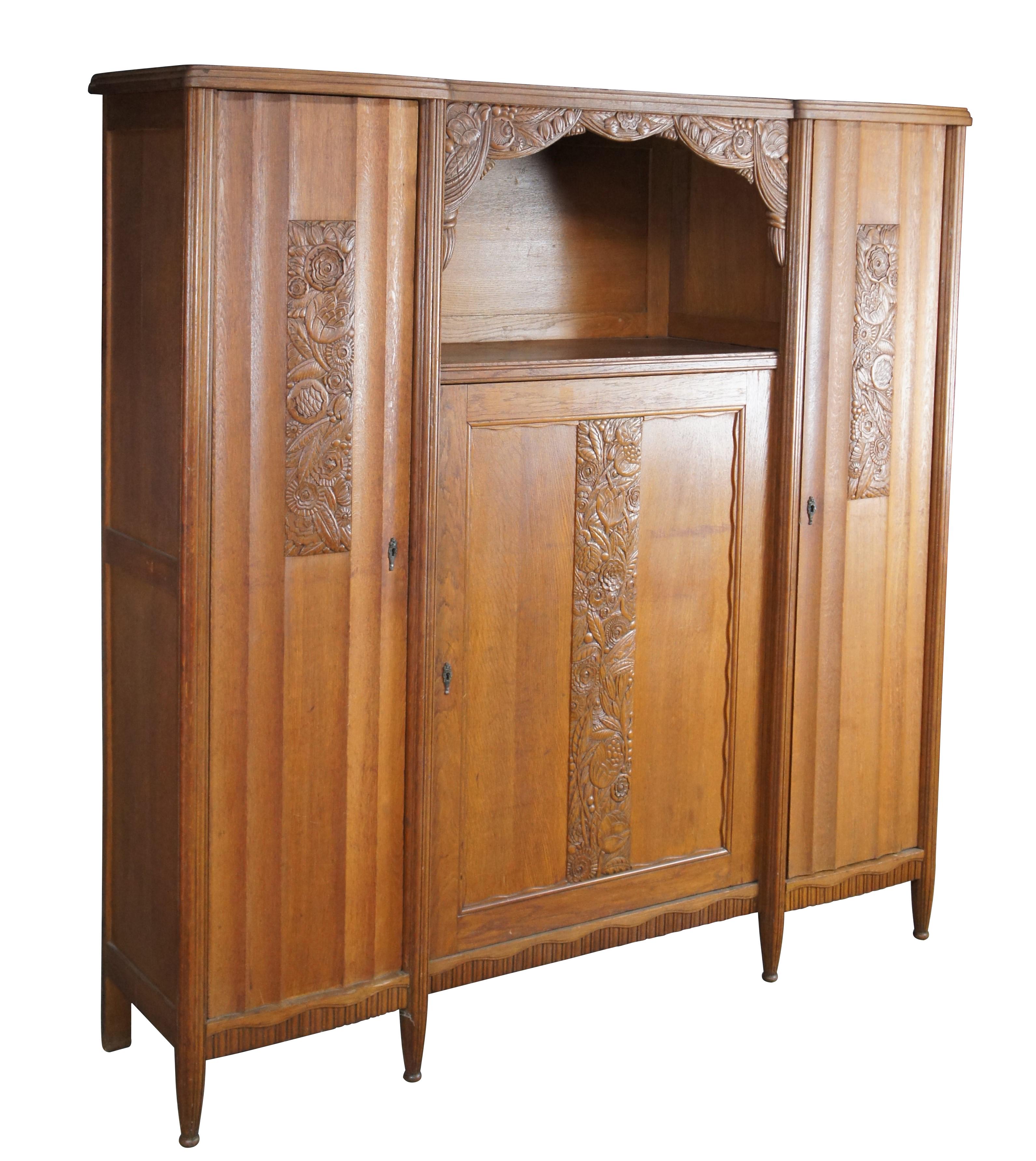 Ancienne armoire / penderie / placard / bibliothèque / armoire à abattage belge.  Fabriquée en chêne, elle présente un design floral sculpté avec une grande étagère supérieure ornée d'un rideau de feuillage, flanquée de deux portes qui s'ouvrent sur