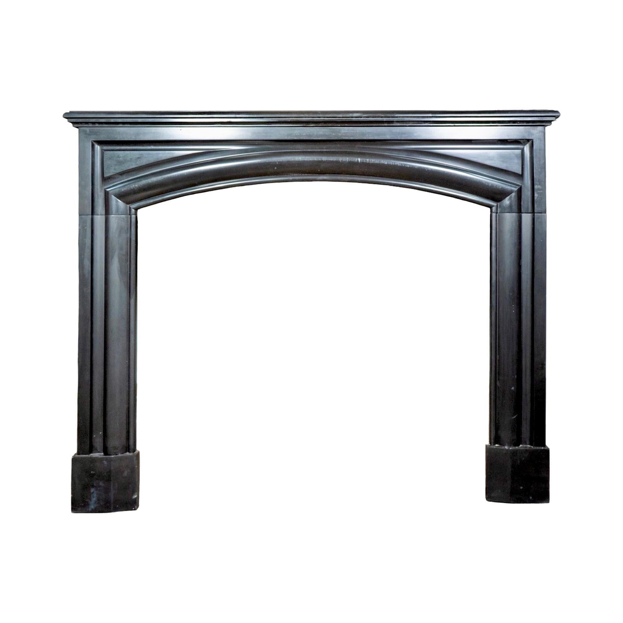 This antique mantel comes from Belgium and is carved from Noir de Mazy, a rare black marble known for its deep tone and subtle veining. Dating back to the 19th century, it has a strong, simple design with an arched frieze and clean lines that give