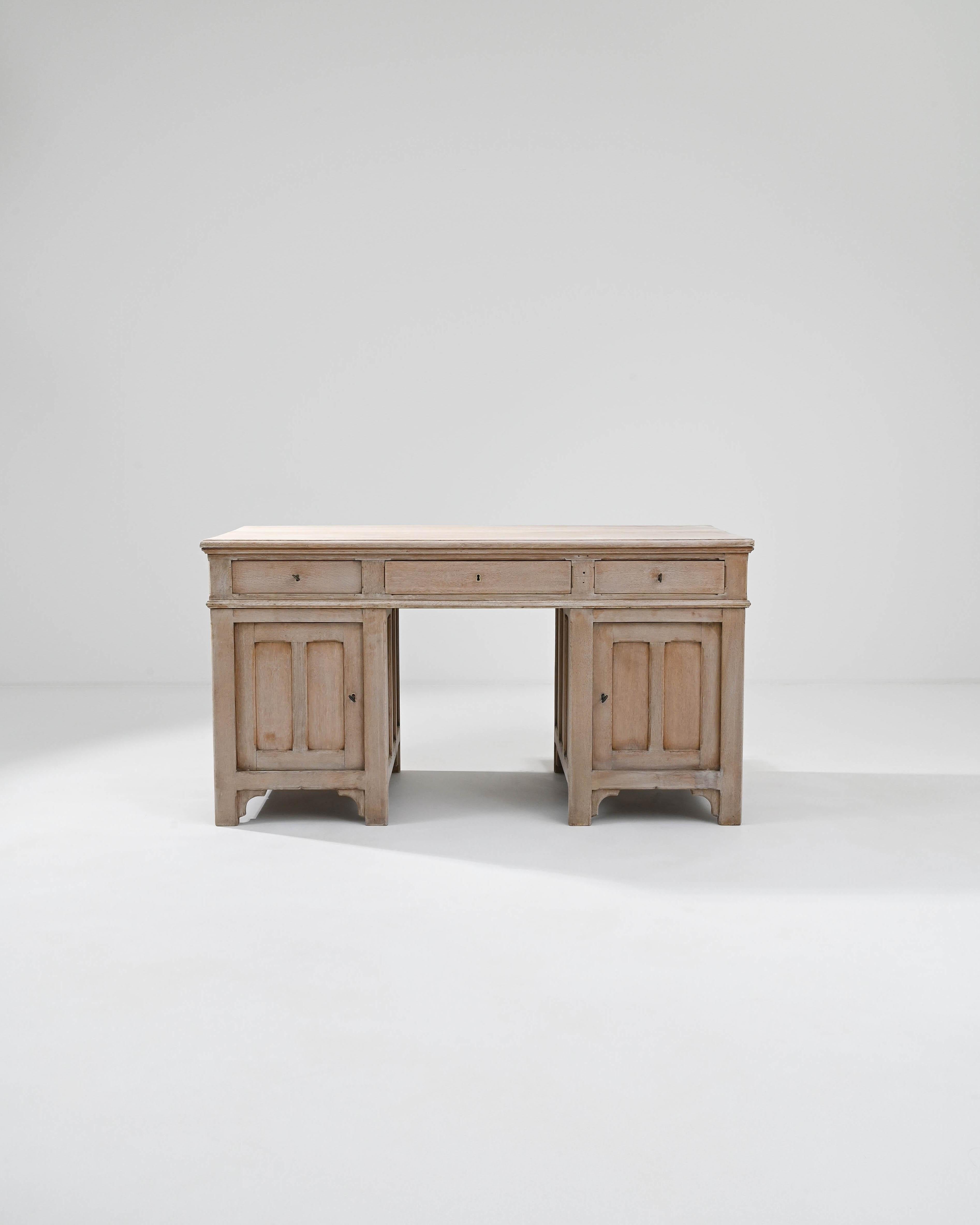 A wooden desk made in Belgium, circa 1900. This ‘kneehole’ type desk, a style first made in England at the 18th century, has two typical flanking storage compartments that form a distinctive nook; allowing a seat to be pulled up to the writing
