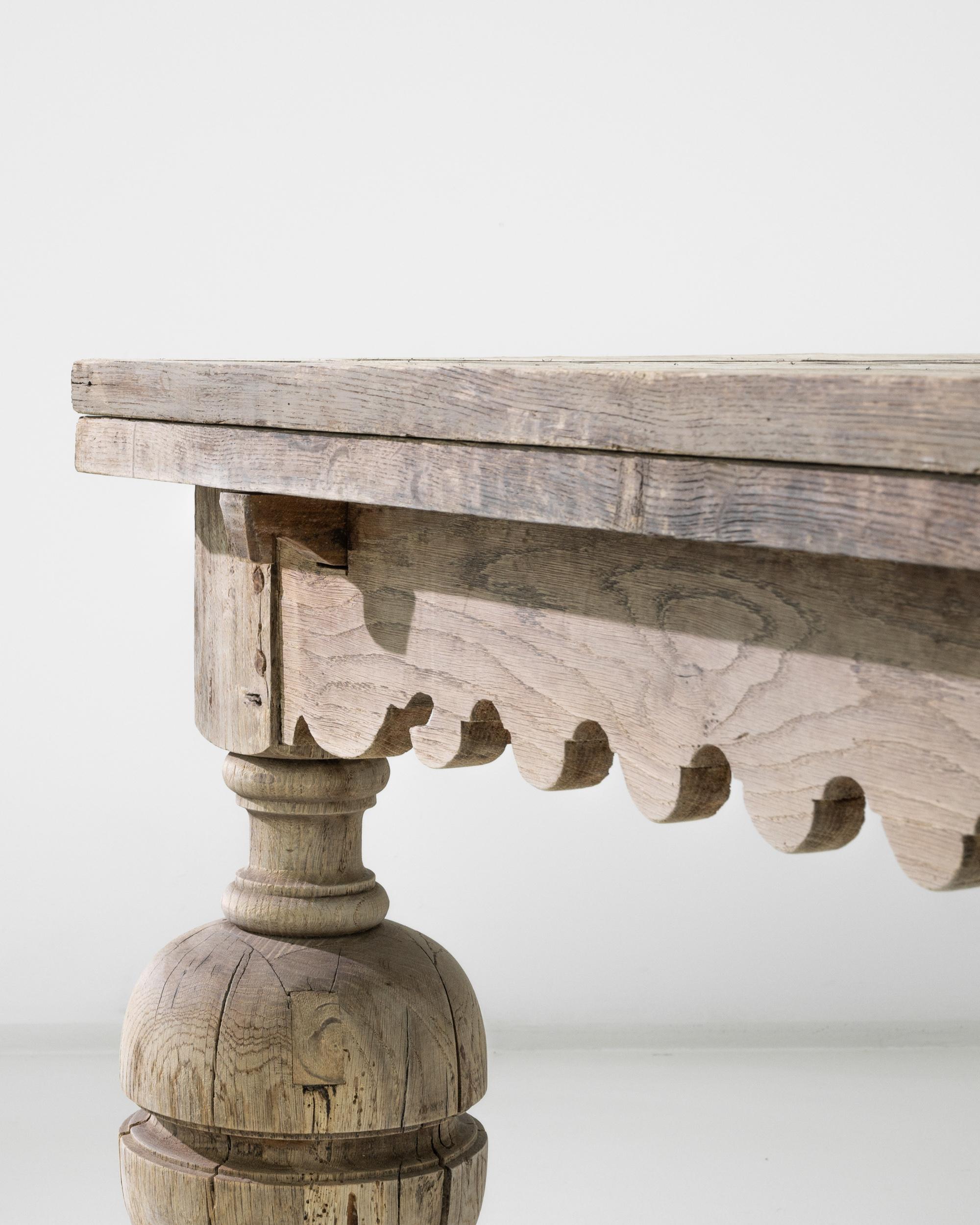 A twentieth-century bleached oak dining table with expandable leaves. This large dining table is full of character, featuring a sawtooth-patterned skirt, bulbous lathed legs, and an expertly applied new bleached finish. With its leaves outstretched,