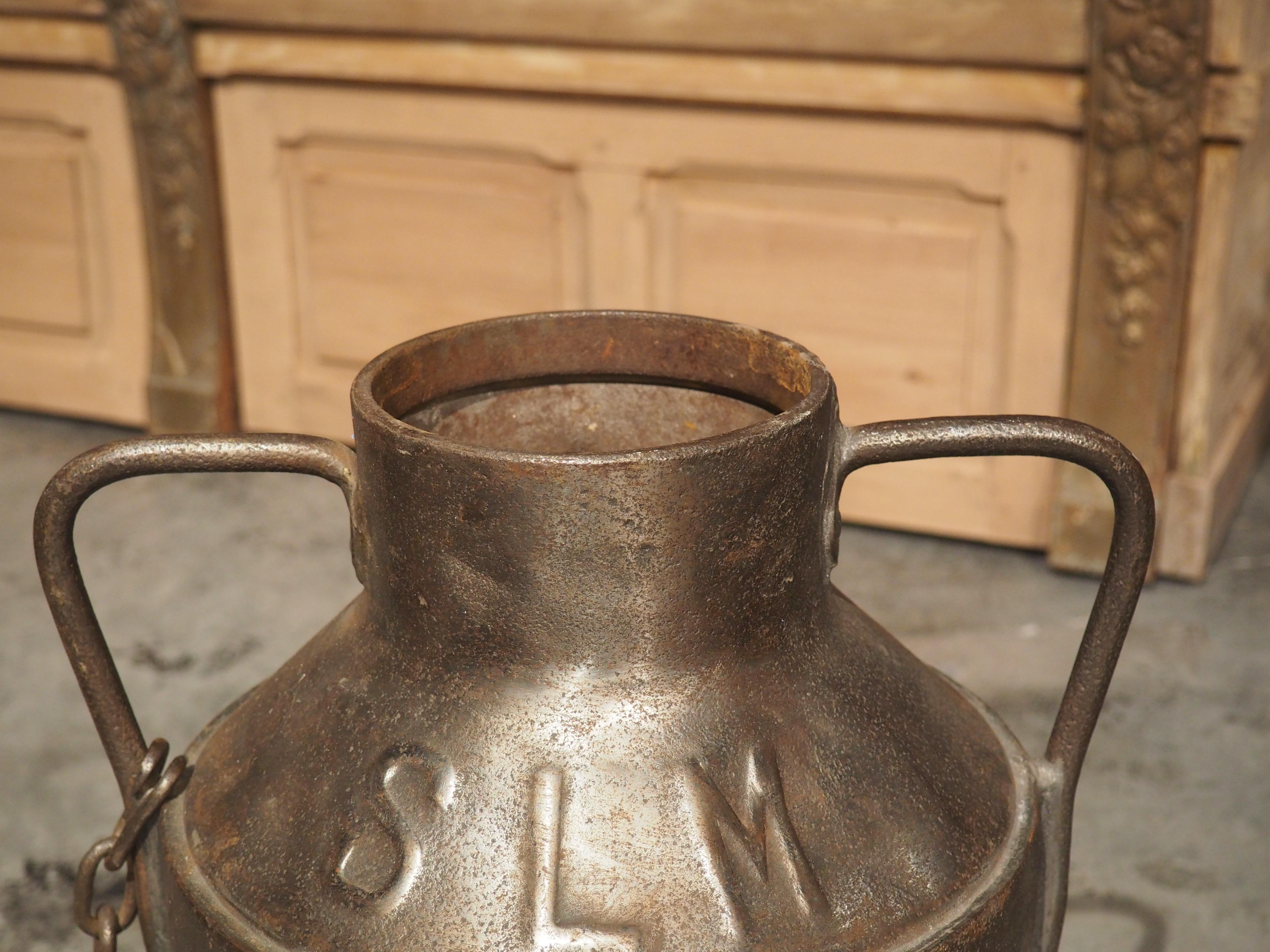 When dairy farmers traveled to the market, they would use large metal jugs, such as this cast iron milk container, to sell milk to local customers. The cast iron has been stamped on the side wall with “SLM”, which is the production mark of a Swiss