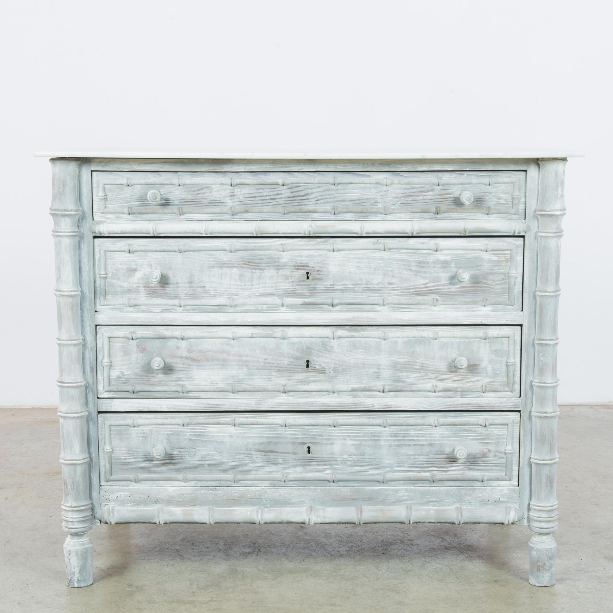 Made in Belgium, the pale teal-gray patina and white marble top of this extraordinary find imparts a calm and rustic touch. The beautifully textured wood grain remains visible, shining through the timeworn paint. The corner columns and drawer