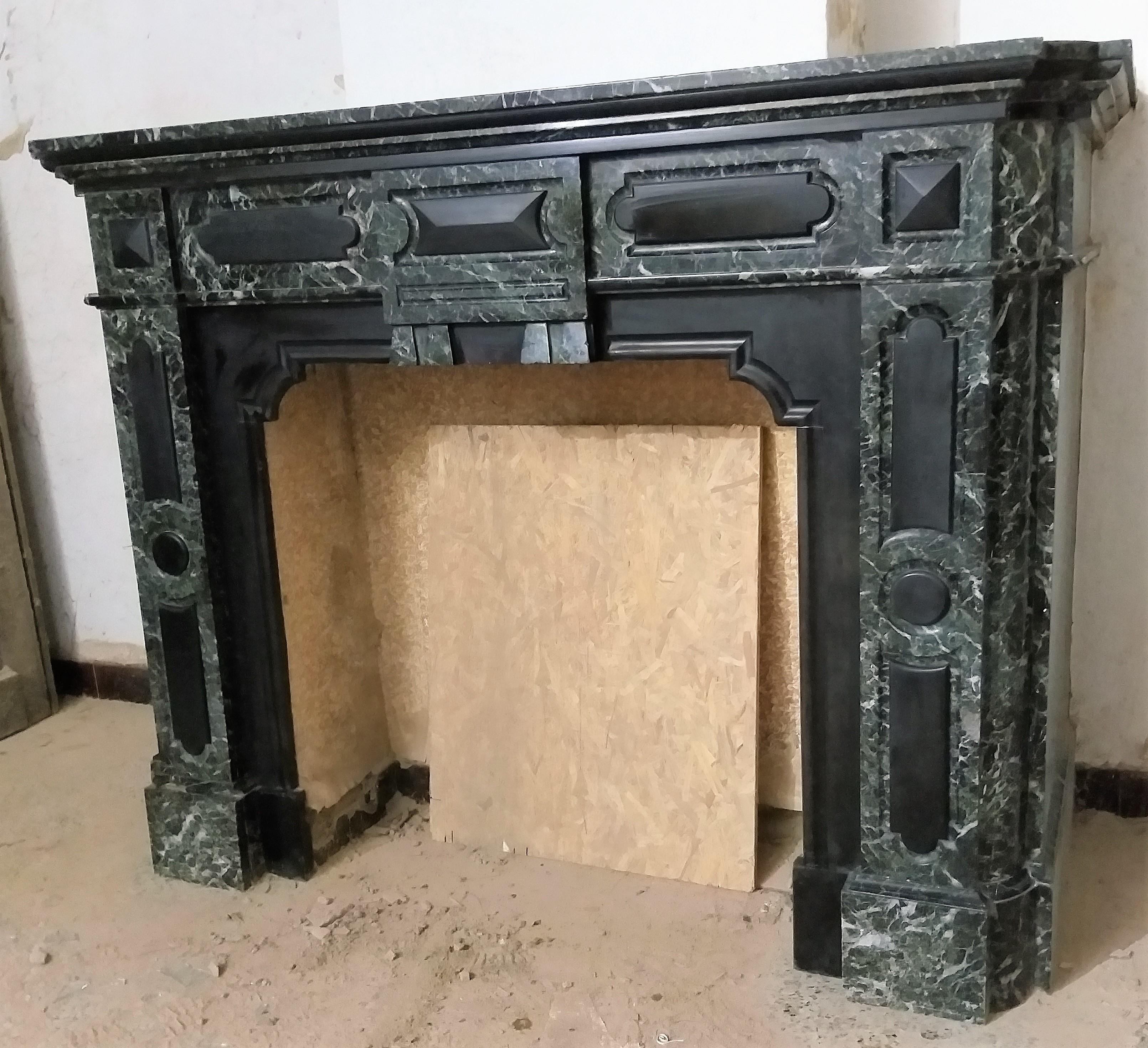 The double moulded breakfront shelf is resting on a boldly carved, Verde Antico fireplace. Enhanced with Belgian Noir de Mazy marble, foyer and panels. The round cornered jambs are making a stylish, massive impression. Removed from a building in