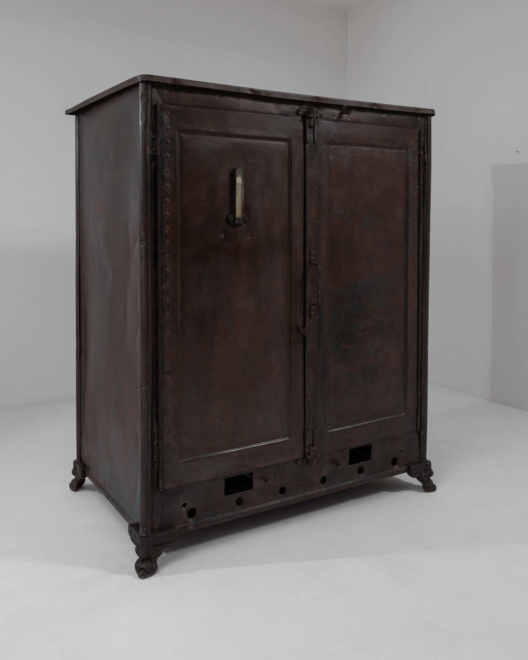 A metal cabinet made in Belgium circa 1900. The metal doors and sides of this sizable cabinet have ripened with age, a subtle glowing oxidized patina spreading across the curiously seasoned material. The doors are equipped with insulated paneling,