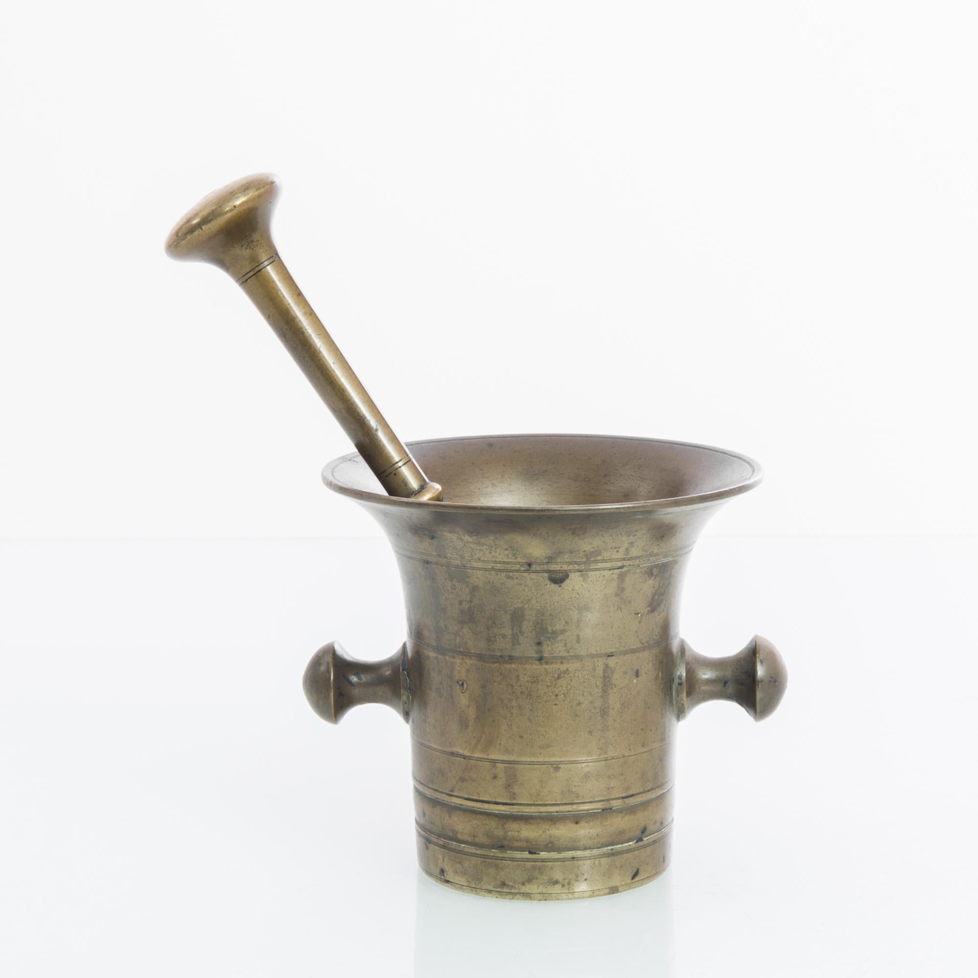 This antique metal mortar with a pestle was made in Belgium and displays a beautifully weathered patina. Often used in apothecaries, these heavy mortars would have been used to prepare medicinal ointments in the past. The mortar features a slightly