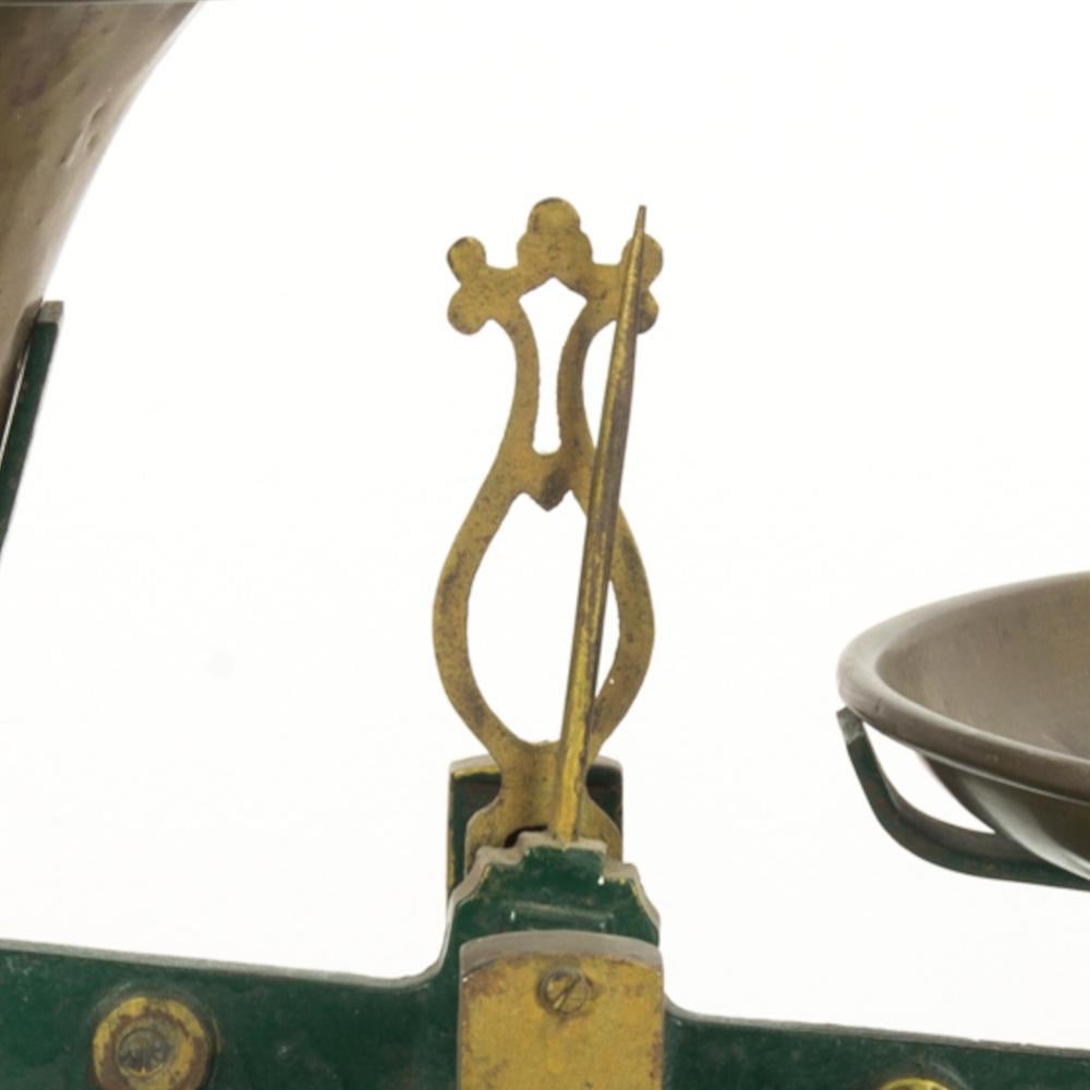 This metal scale was made in Belgium. With its beautiful patina and center finial, it will bring a rustic and quaint character to any space. The scale comes with two dishes, one slightly deeper. Its slightly elevated base is painted green and yellow
