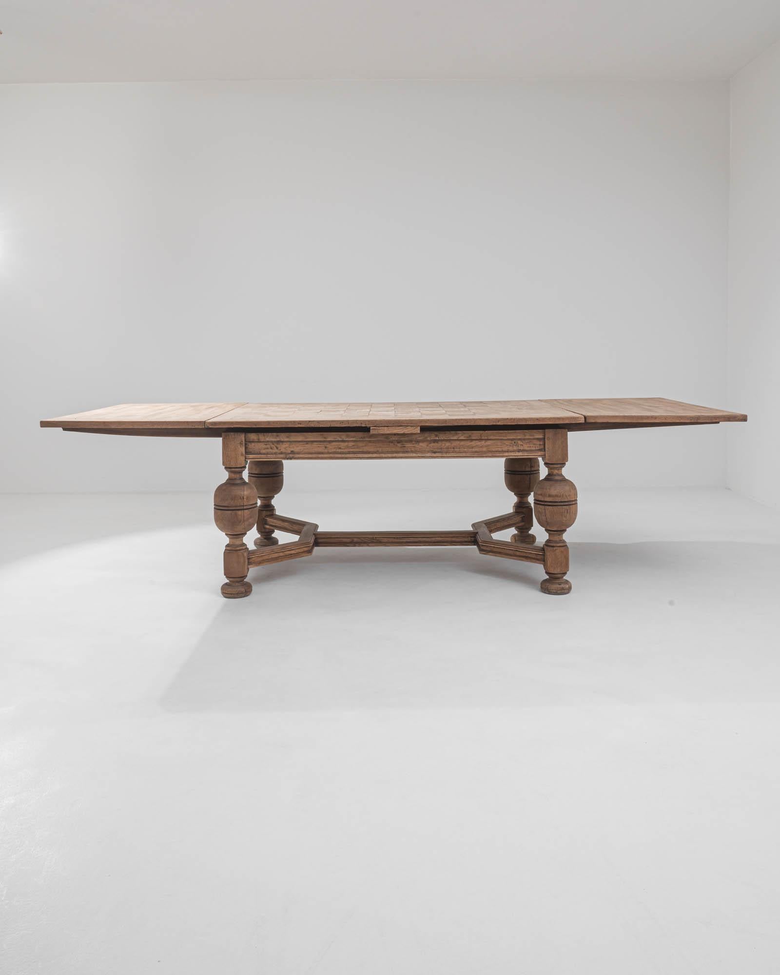 A folding wooden dining table created in 1900s Belgium. Characteristic of classic Belgian style, this table blends a sturdy solid construction with thoughtful, elegant design. The leaves of this table extend outwards to create an enormous dining