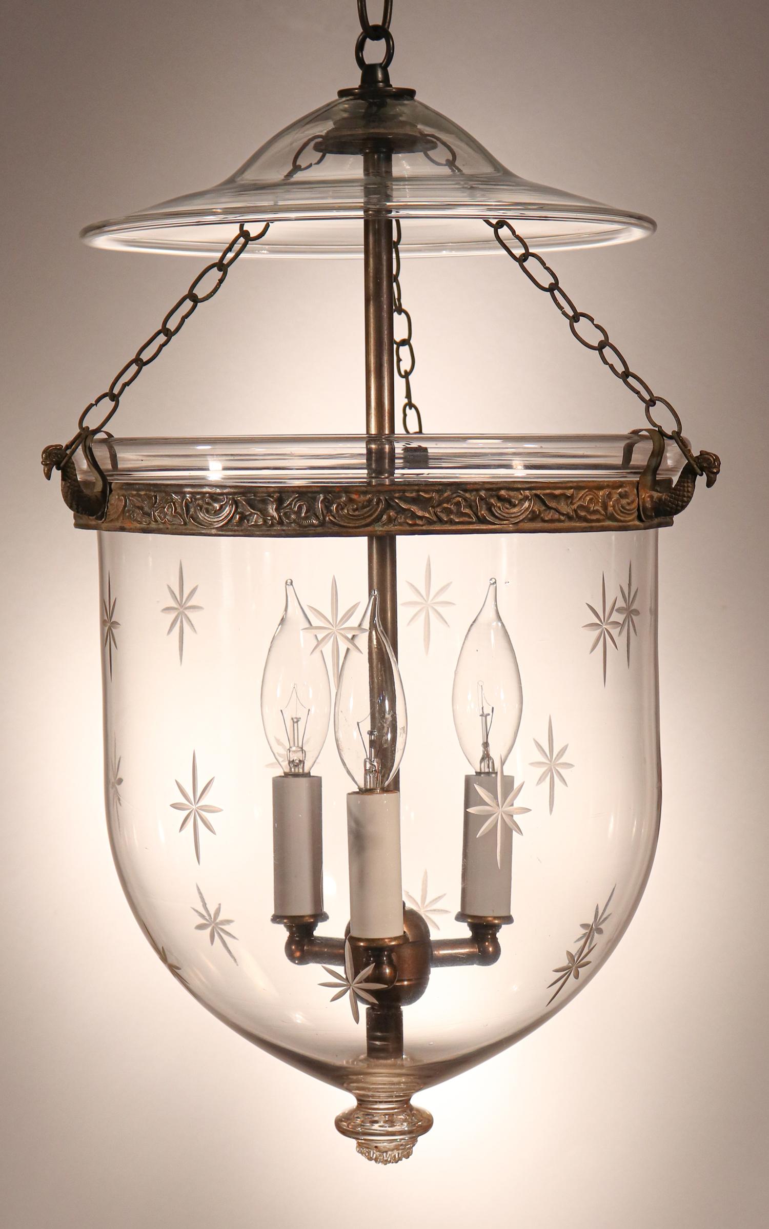 An antique English bell jar lantern with distinctive form and a cut-glass star motif. This circa 1870 lantern features excellent quality hand blown glass with desirable air bubbles in the bell jar. The embossed brass band, which has a leaf design,