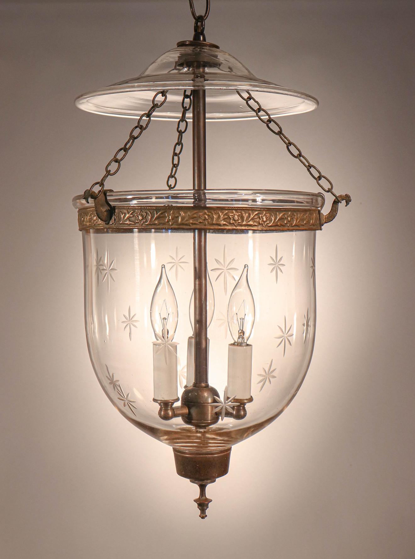 This circa 1870 hand blown glass bell jar lantern has lovely form accentuated by a finely etched star motif. It features all original brass fittings, including the embossed brass band and finial/candleholder base. The pendant light has been newly
