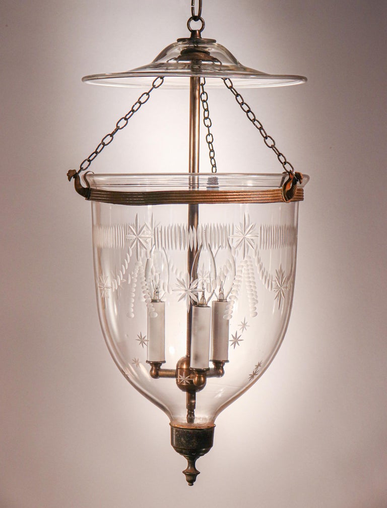 An antique English bell jar lantern with elegant form and an etched Federal-style design. This circa 1860 pendant light features excellent quality hand blown glass and all-original fittings—including glass smoke bell/lid, rolled brass band, and