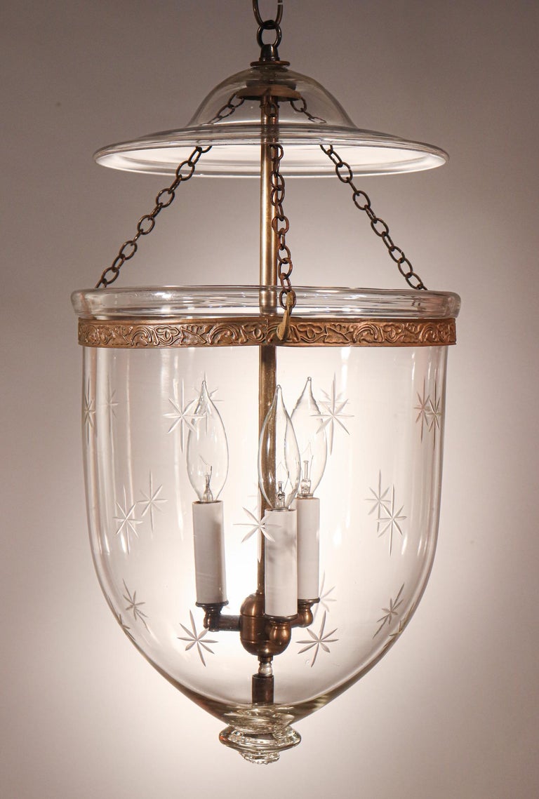 An antique English bell jar lantern featuring very good quality hand blown glass and a cut-glass star motif that complements the attractive form of this circa 1890 pendant. The brass band, which has an embossed floral design, was replaced at some