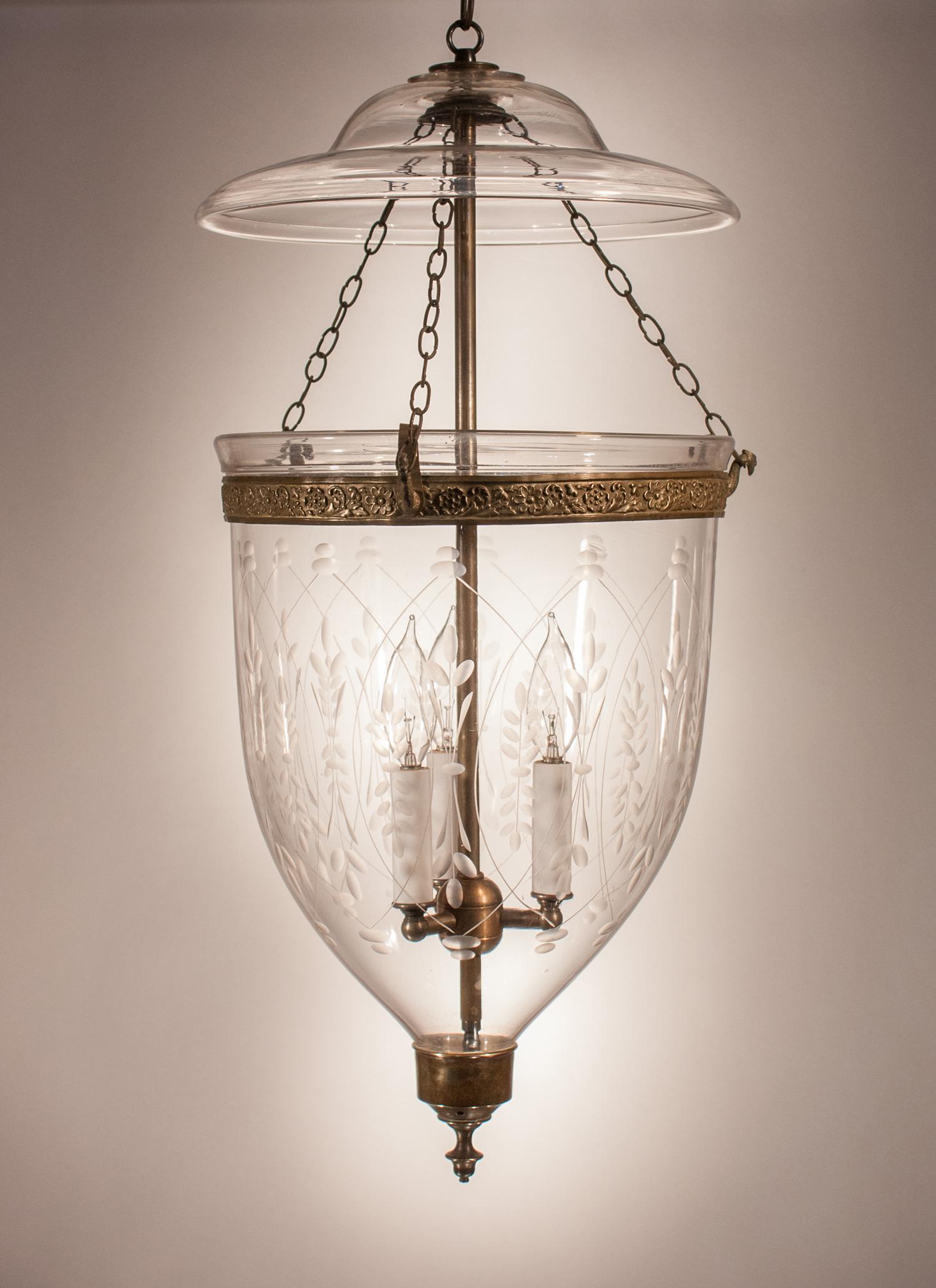 A larger-sized English bell jar lantern with classic form and high-quality handblown glass, circa 1840. This bell jar pendant features all-original fittings, including its smoke bell/lid, embossed brass band, and brass candle holder finial base. The
