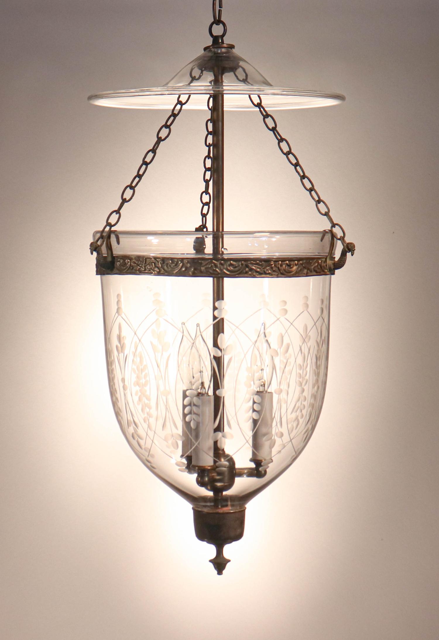 An elegant antique English bell jar lantern with very good quality hand blown glass and an etched wheat motif. This circa 1860 pendant features its original chains, brass finial/candleholder base, and glass smoke bell. The brass band, which has an