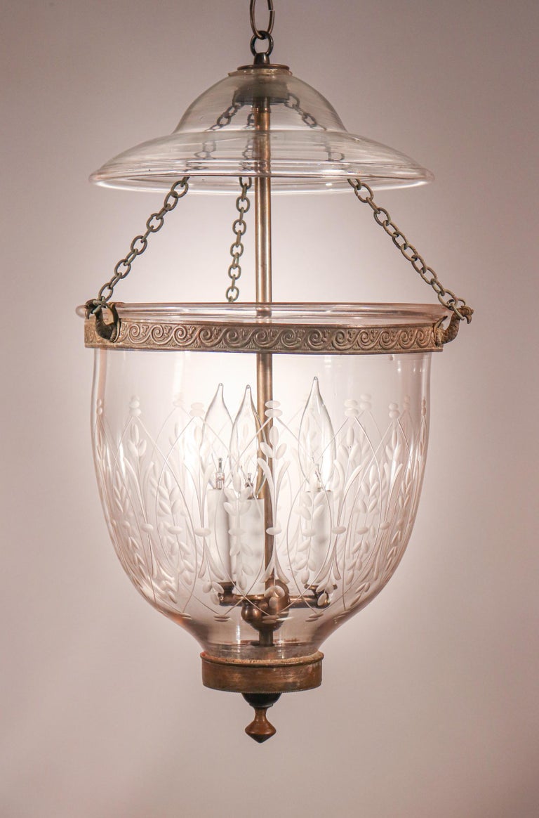 A distinctive lantern in our bell jar collection. This circa 1860 English pendant light features generous form and excellent quality hand blown glass that is etched with a wheat motif. In addition, the authentic brass finial/candleholder base and