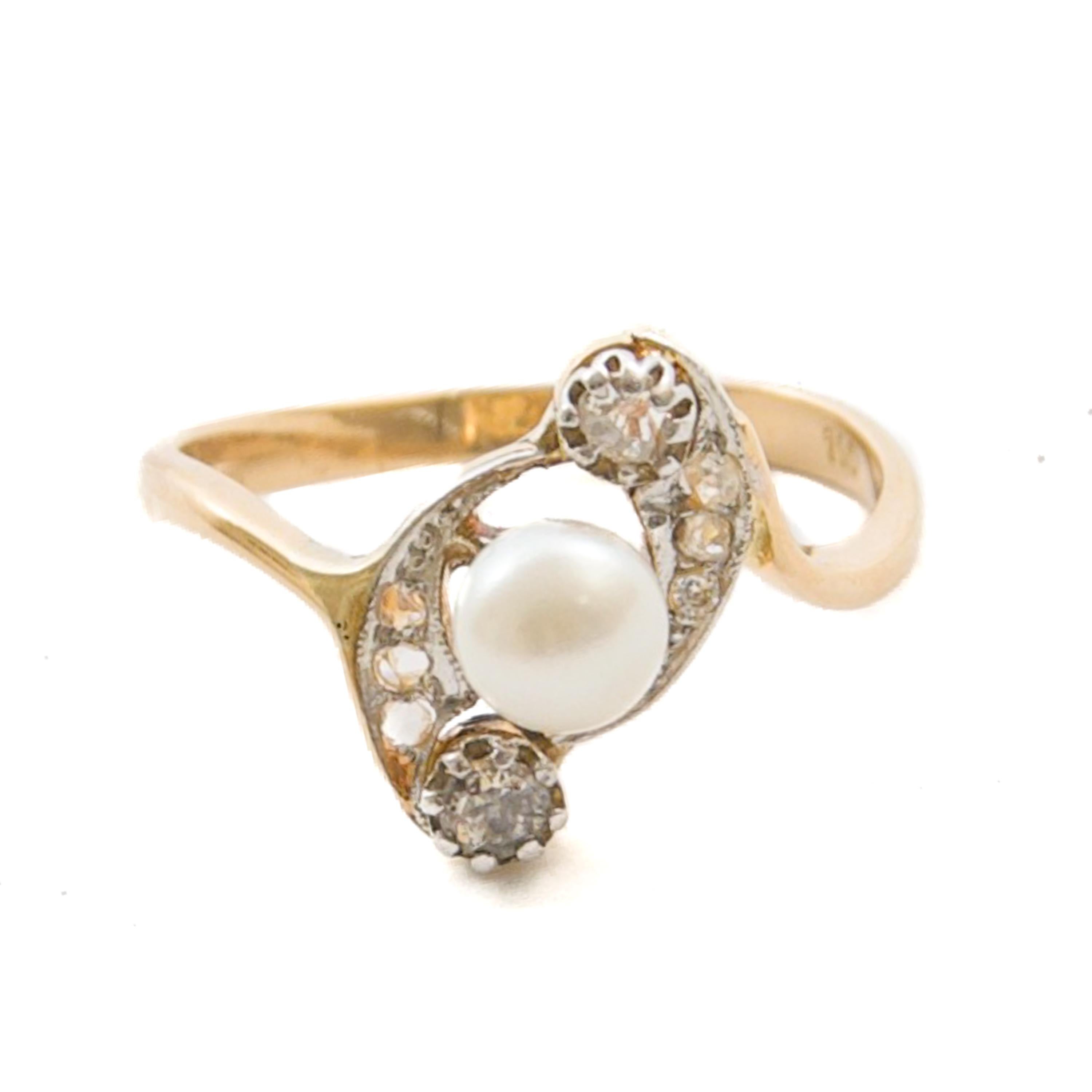 Cette élégante bague de l'époque de la Belle Époque est réalisée en or jaune 14 carats et présente une combinaison raffinée de matériaux et de design. En son centre se trouve une perle naturelle lumineuse d'environ 5,3 mm de diamètre, entourée d'un