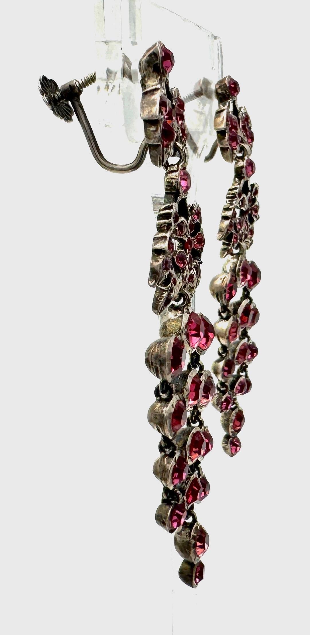 Questi orecchini pendenti sono stati creati nel 1910-1920 circa. La parte superiore è dotata di viti nascoste da un paio di foglie di vite. Il retro della vite è disegnato come un fiore. Sospeso alle foglie di vite c'è un grande acino articolato con