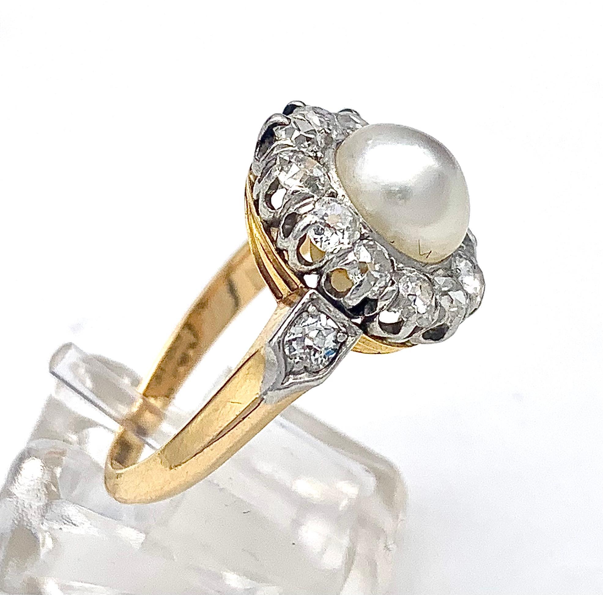This ring is made out of 18 karat yellow gold and platinum the ring head features ca natural oriental button pearl surrounded by lovely white diamonds, all set in platinum. The ring shoulders are also decorated with a diamond each set in platinum. 