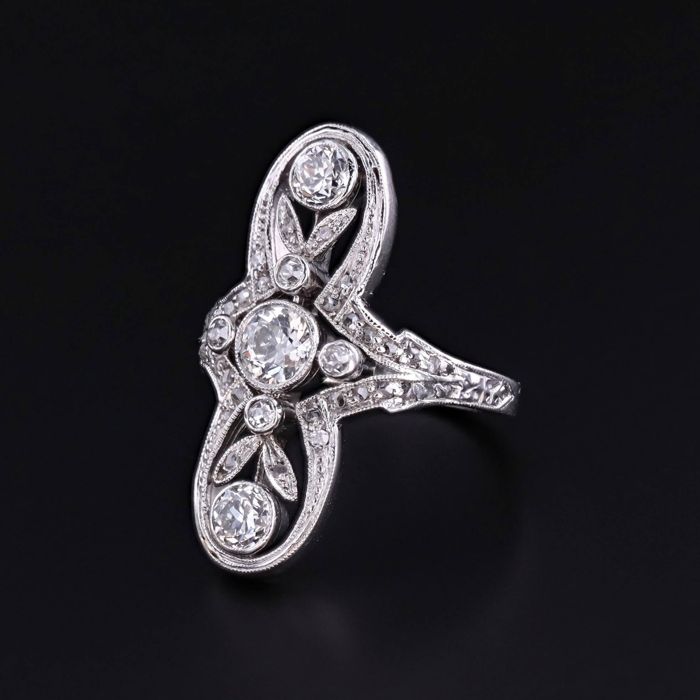 Raffinée et romantique, cette bague ancienne (vers 1900) présente un délicat motif floral de diamants sertis en platine, un métal précieux prisé au début du siècle pour sa solidité et sa brillance. La bague comporte un diamant de taille européenne