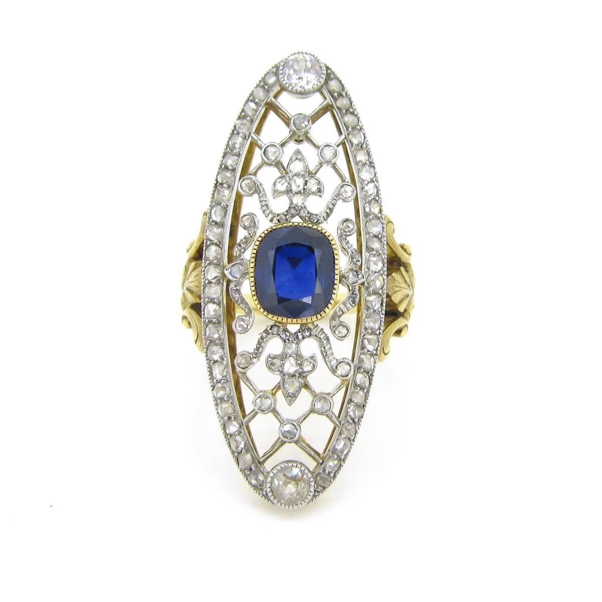 This amazing ring features in its center a deep blue sapphire set into a millegrain 18kt gold setting. It is surrounded with a beautiful hairnet and volutes design adorned with rose cut diamonds. The ellipse is magnified with 46 rose cut diamonds