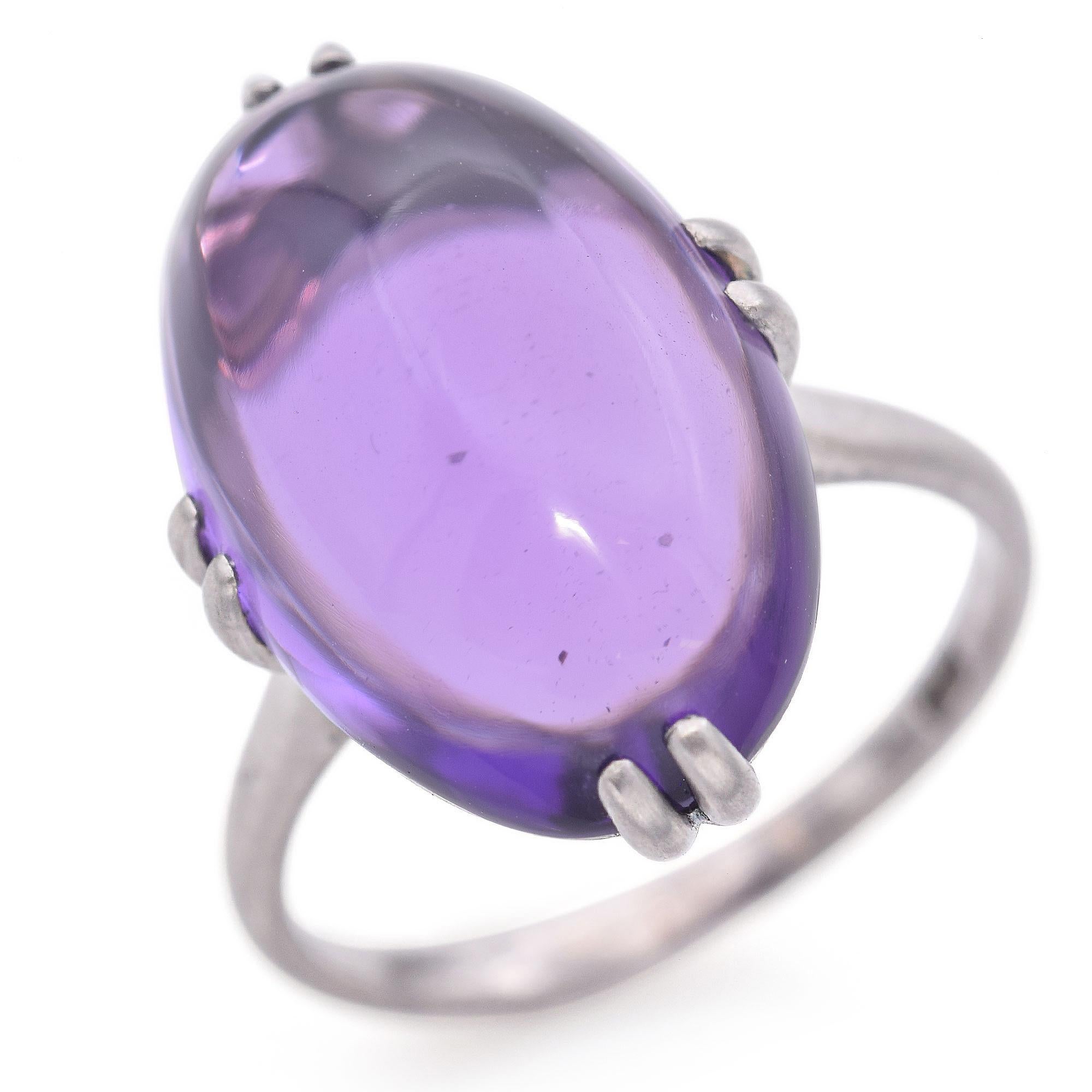 This Belle Époque ring is crafted in platinum. It features a smooth, purple amethyst cabochon weighing approximately 6 carats.
The amethyst is set in a simple, elegant prong setting.

Weight: 4.8 grams 
Stone: 6ct Amethyst 
Measurements: 11.7 x 17.8
