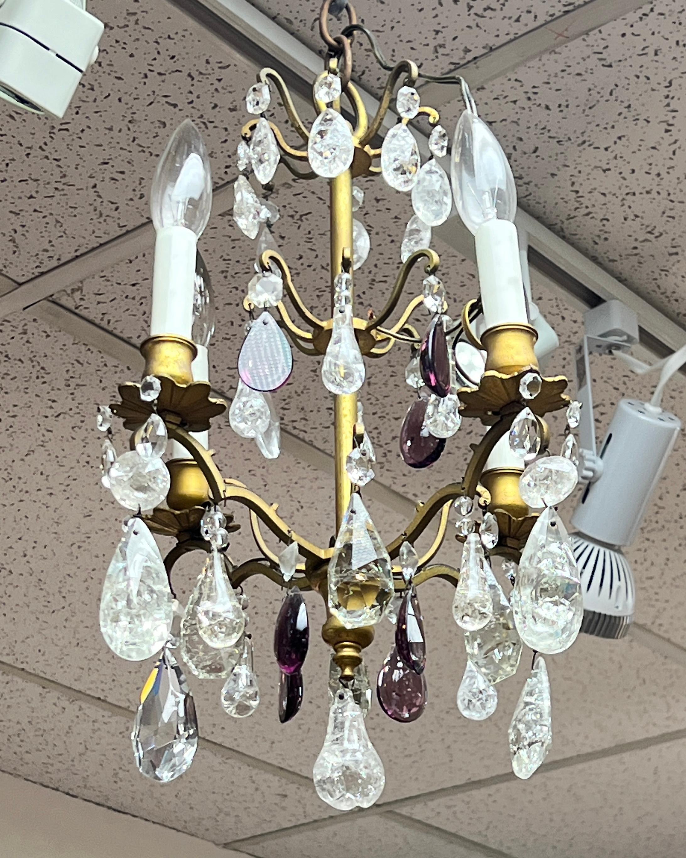 Our petite bronze chandelier in the fashion of Maison Bagues dates from the late 19th to early 20th century. It features glass and rock crystal pendants and violet colored drops and is ready for installation with four electrified candle arms.