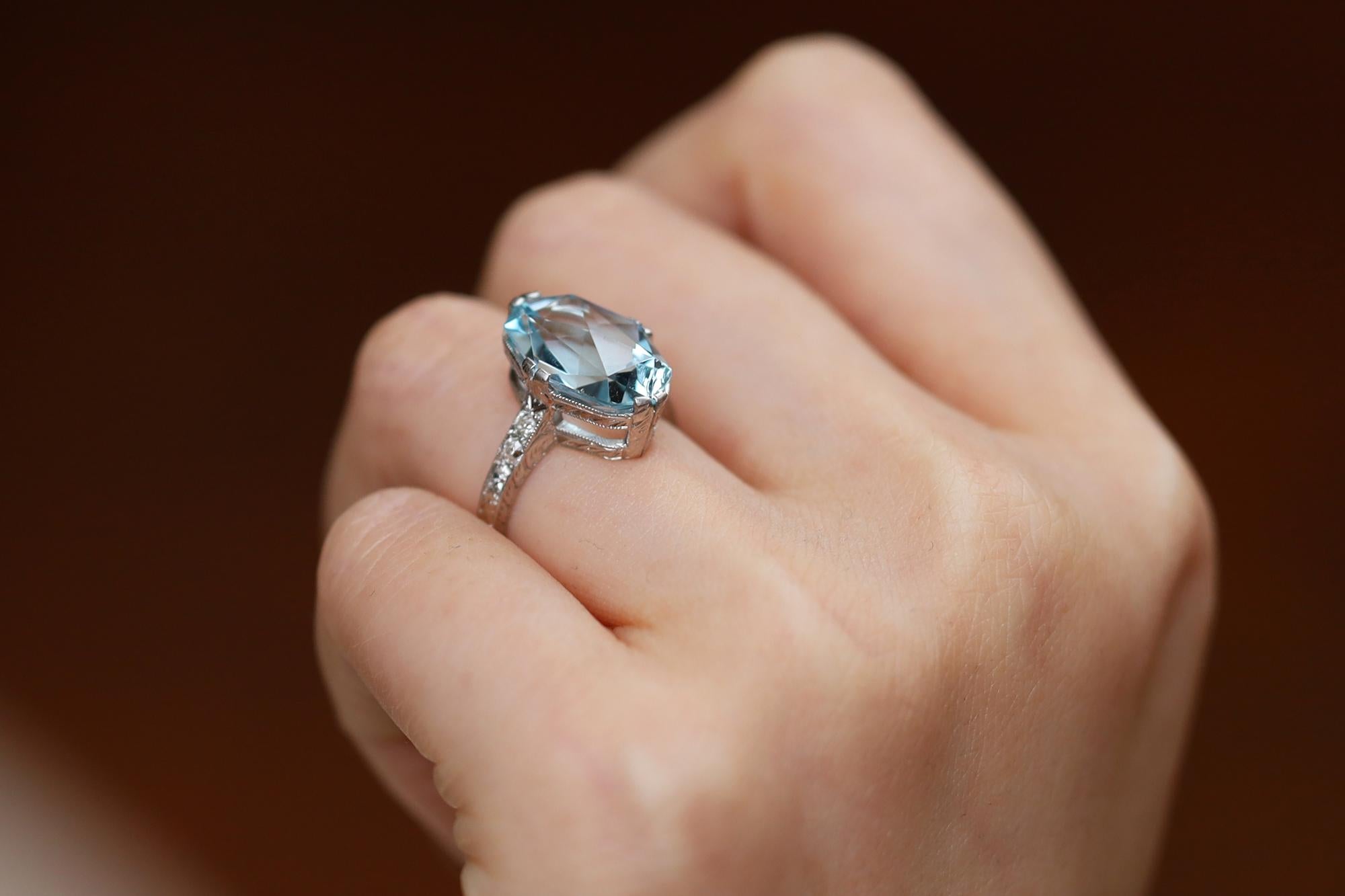 A signed La Graves engagement ring, antique from the resplendent Belle Époque era of the early 1900s. Centered by a 6 carat light blue Aquamarine, expertly cut into a double faceted oval with 6 antique diamonds flanking the natural gem. Crafted with