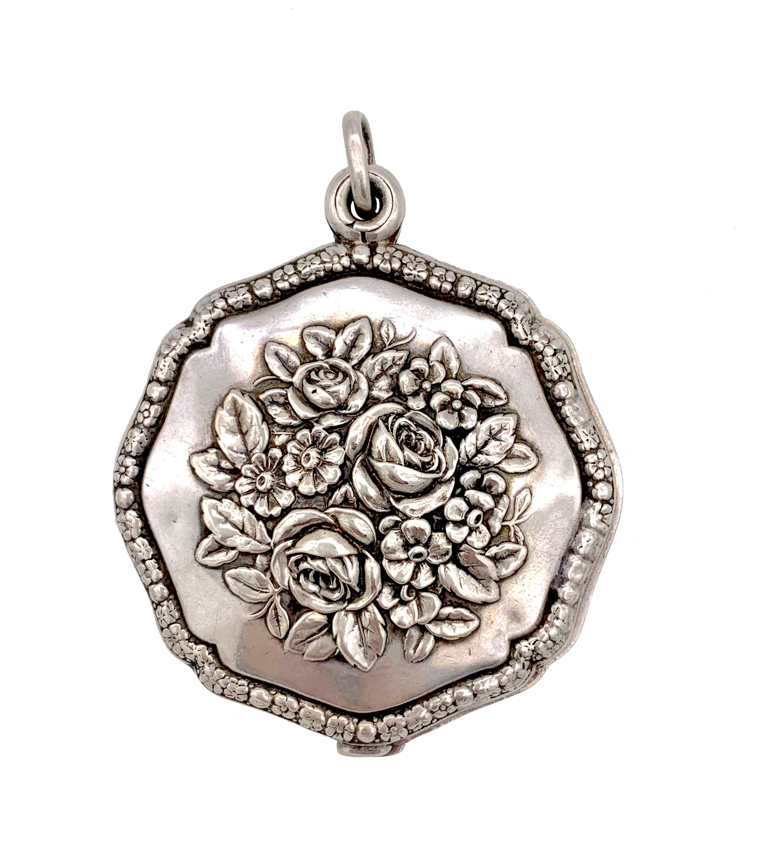 This generous size pendant is designed as a sliding mirror or locket. The locket is decorated on both sides with roses and other flowers and leaves in relief. The borders of the pendant are are designed as a frame of different flowers and flower