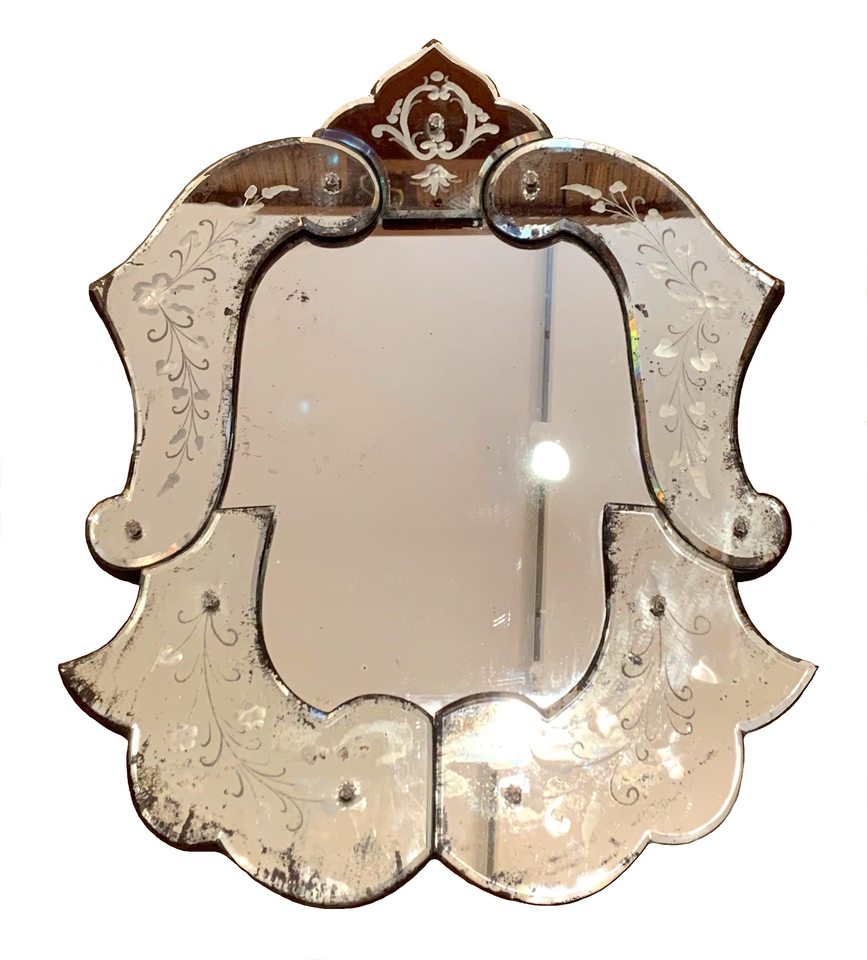 This elegant Belle Époque Venetian wall mirror is finely decorated with etched garlands of ivy tied together with ribbons tied to a bow. The glas is in fine order and original condition. It is mounted on wood and backed with card
The glass shows